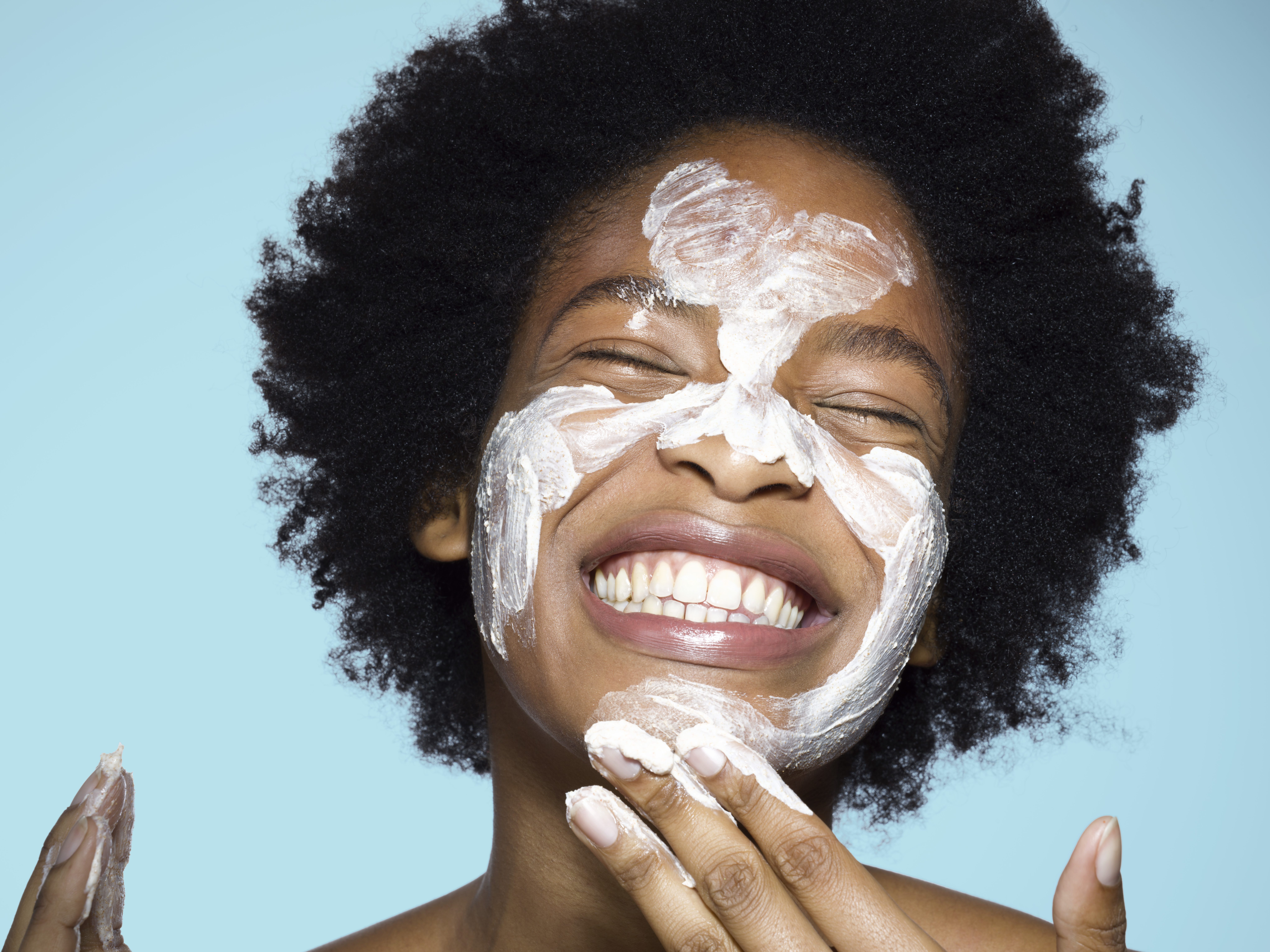 woman washing her face with white lotion skincare black woman with afro