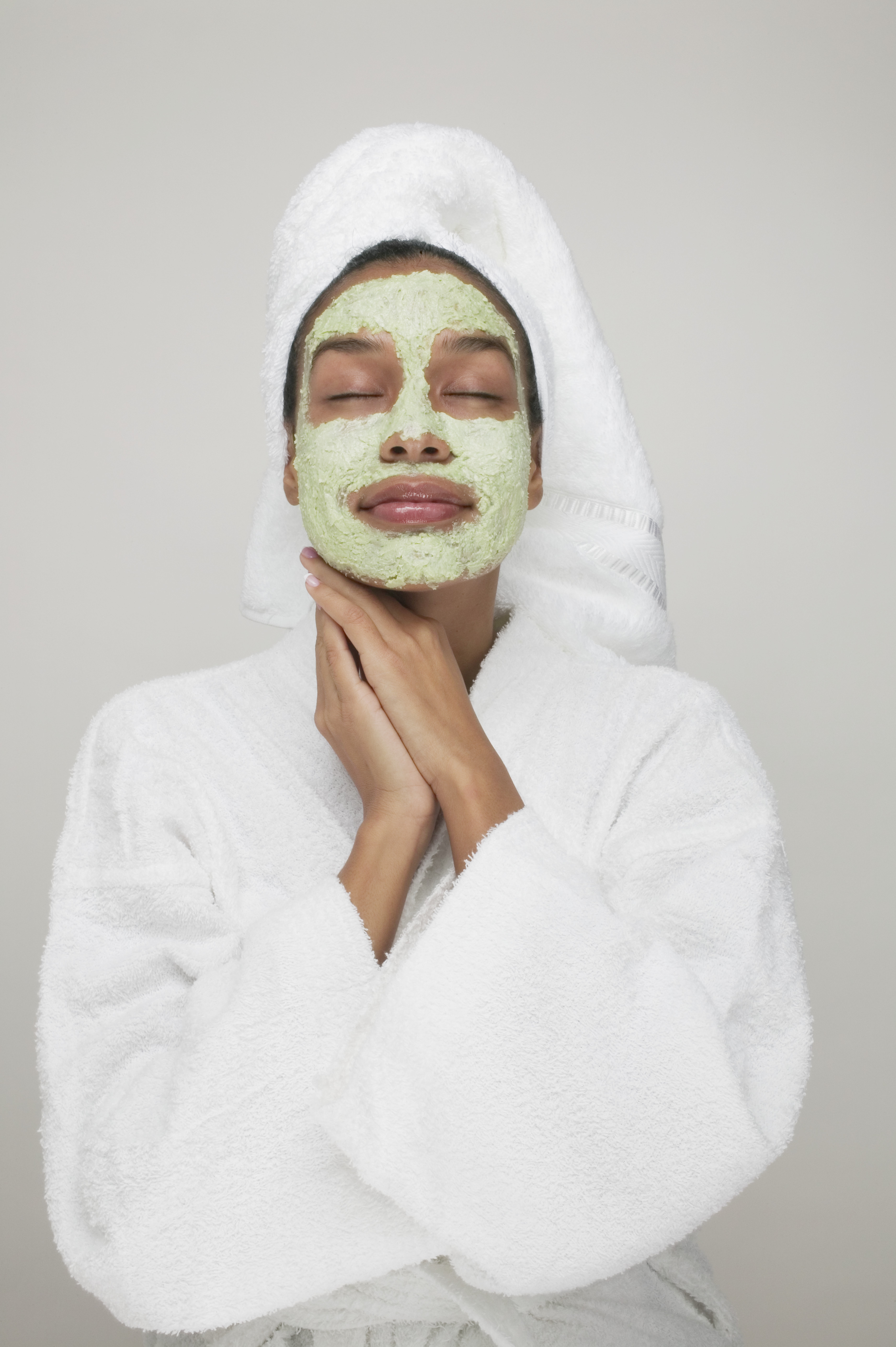 woman wearing a green face mask and white towel spa