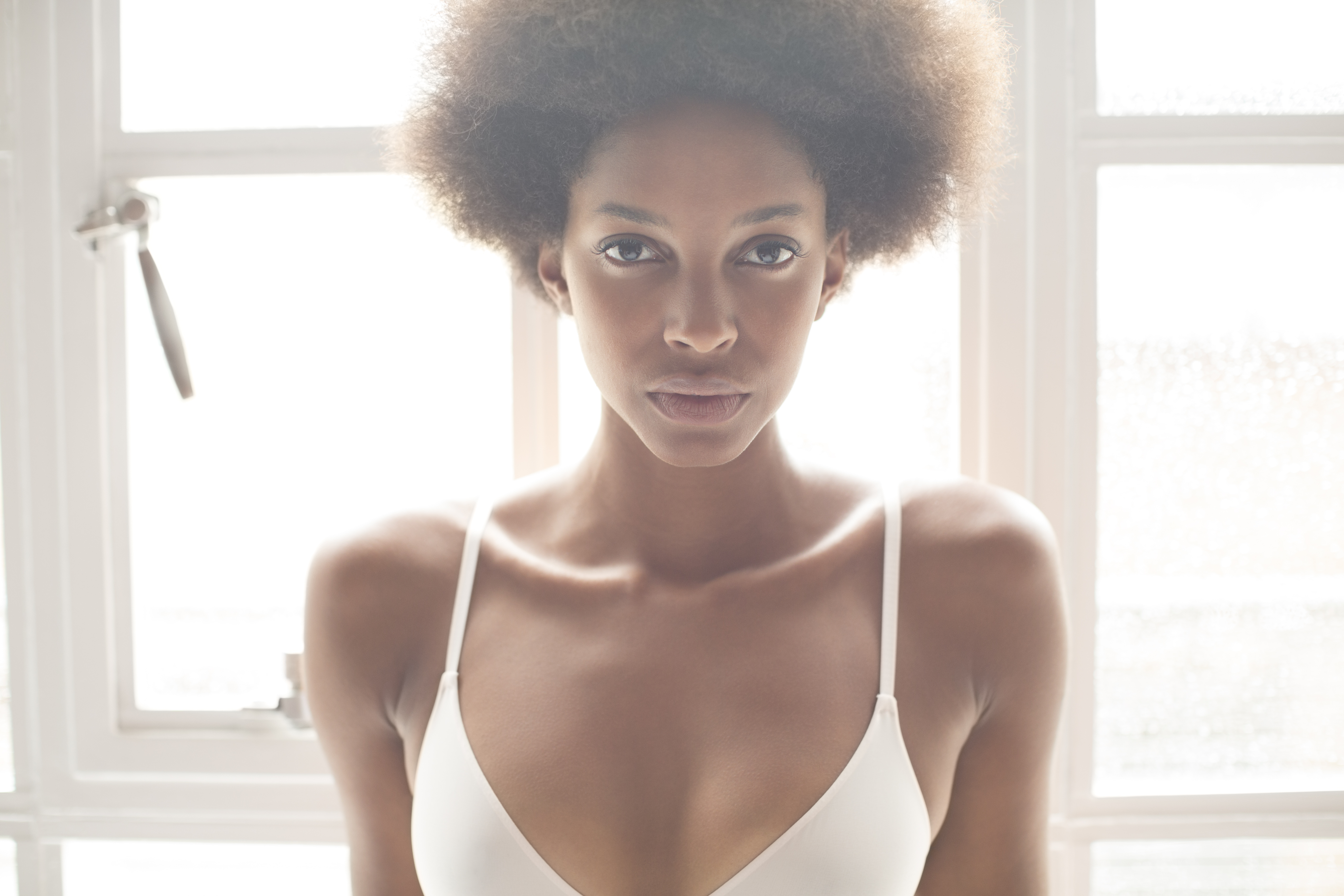 Woman wearing bra in front of window