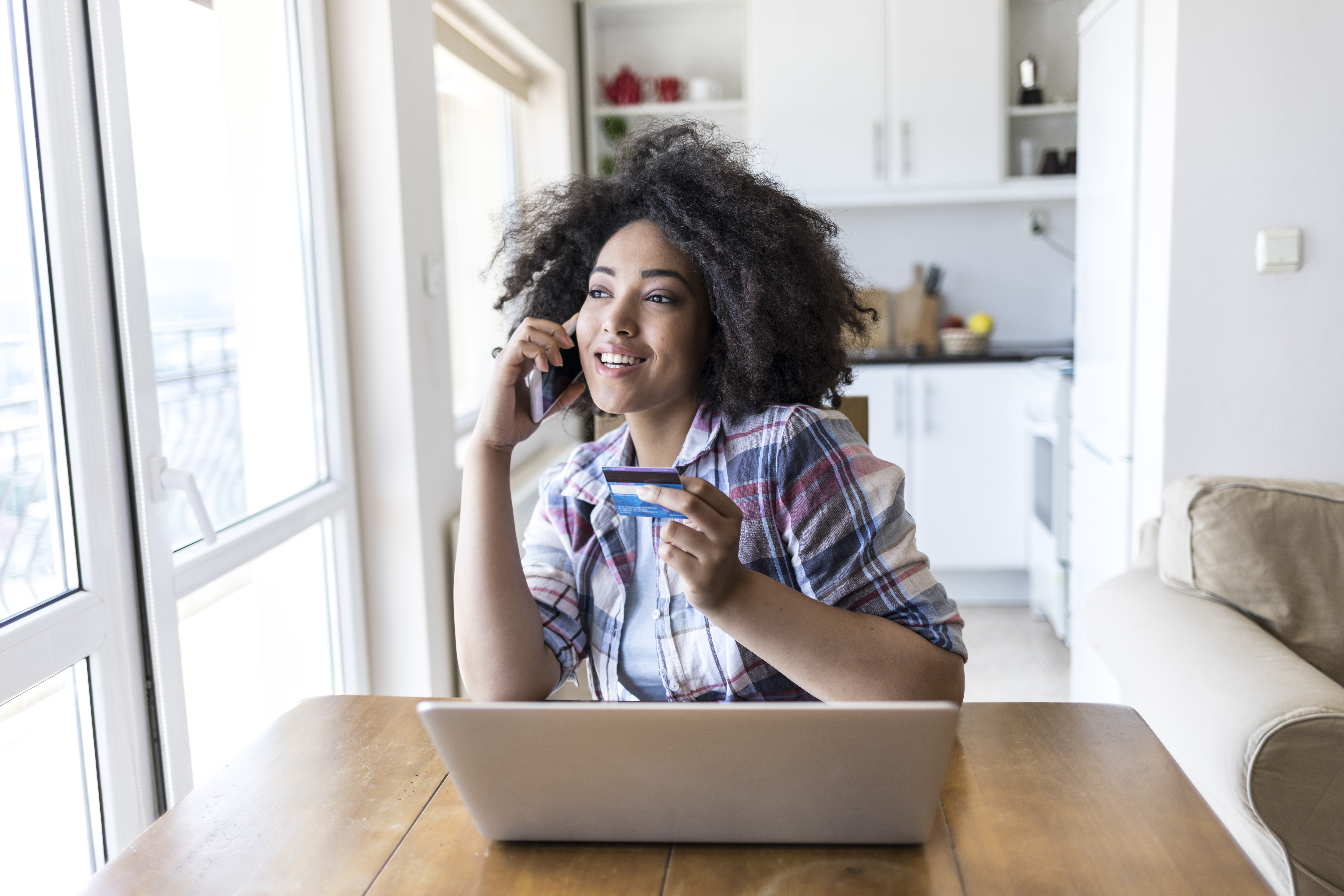 woman holding credit card while on phone