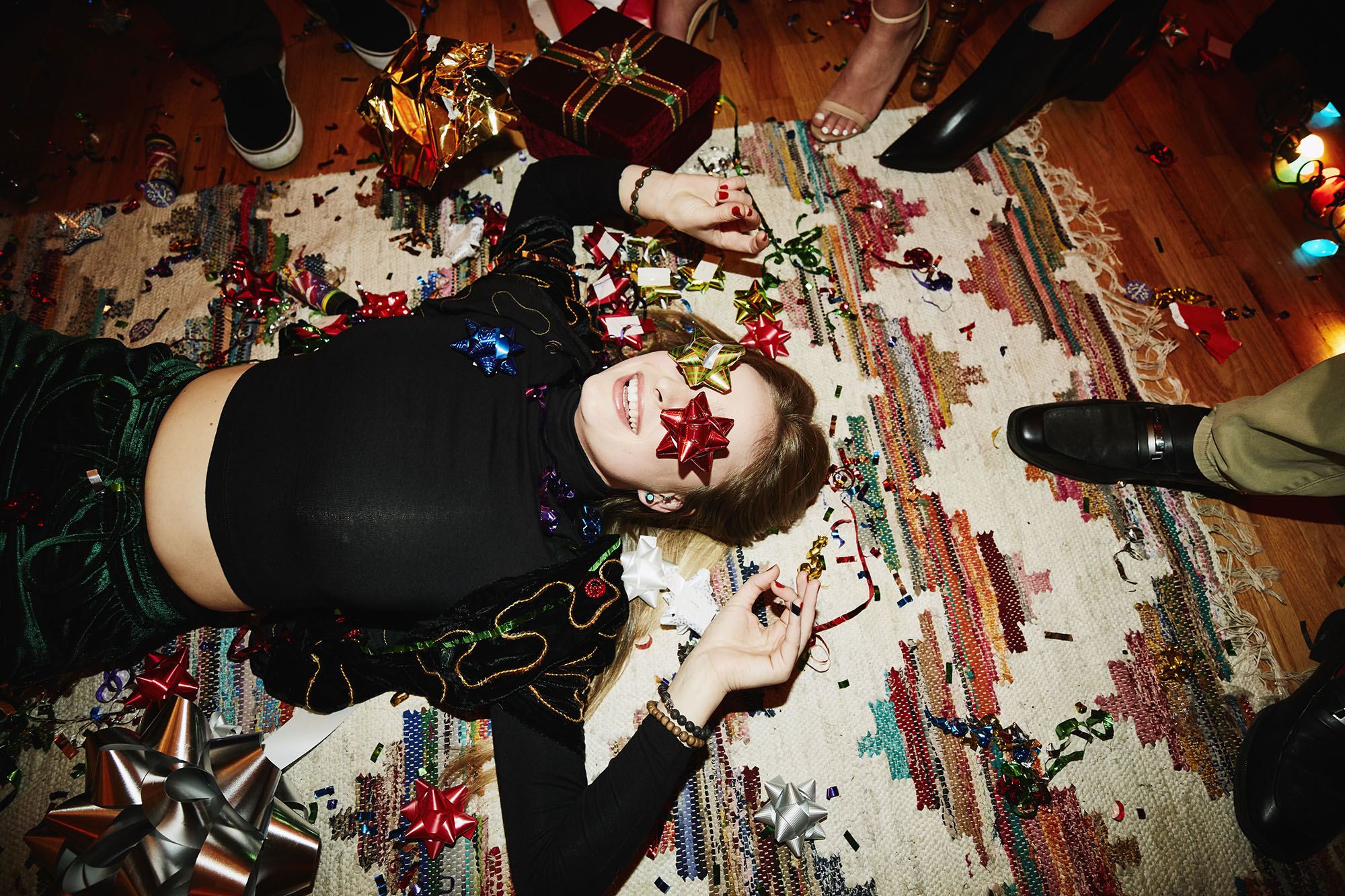 Laughing woman lying on floor with bows over eyes during holiday party with friends