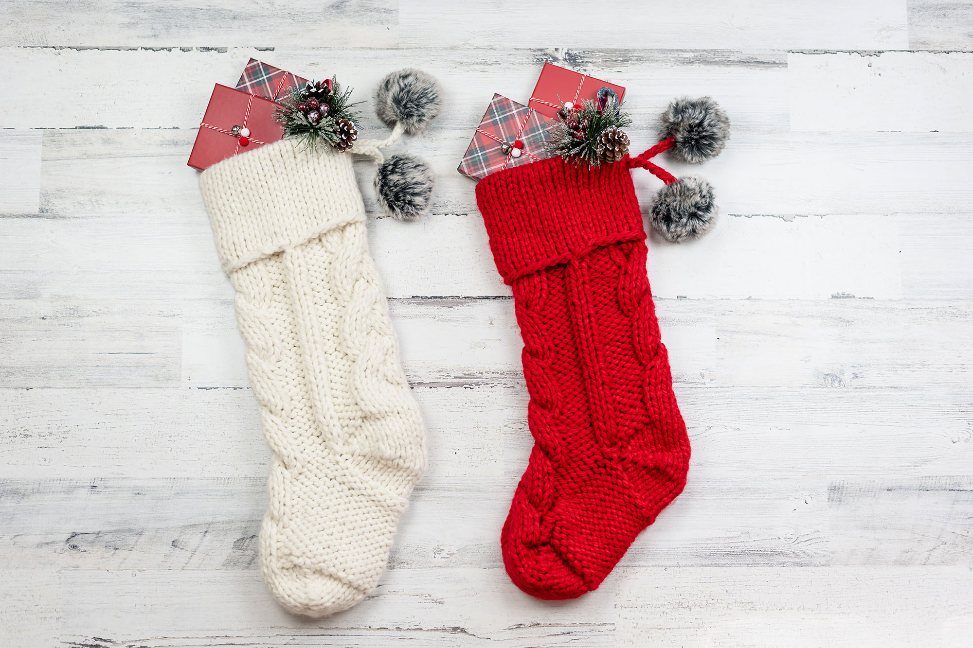 Two knitted Christmas stockings on distressed wood background