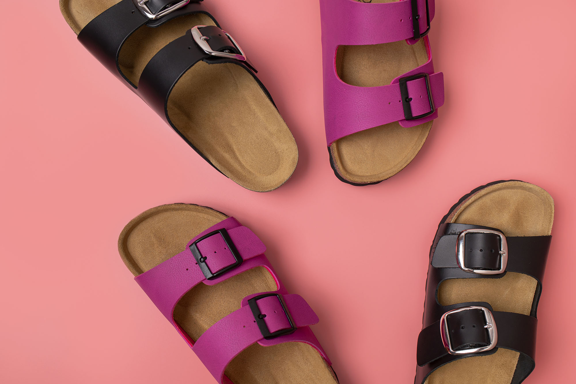 Trendy fashion footwear mockup. Leather pink and black sandals birkenstocks on pink background top view flat lay. Unisex summer shoes, genuine leather flip flops with cork soles