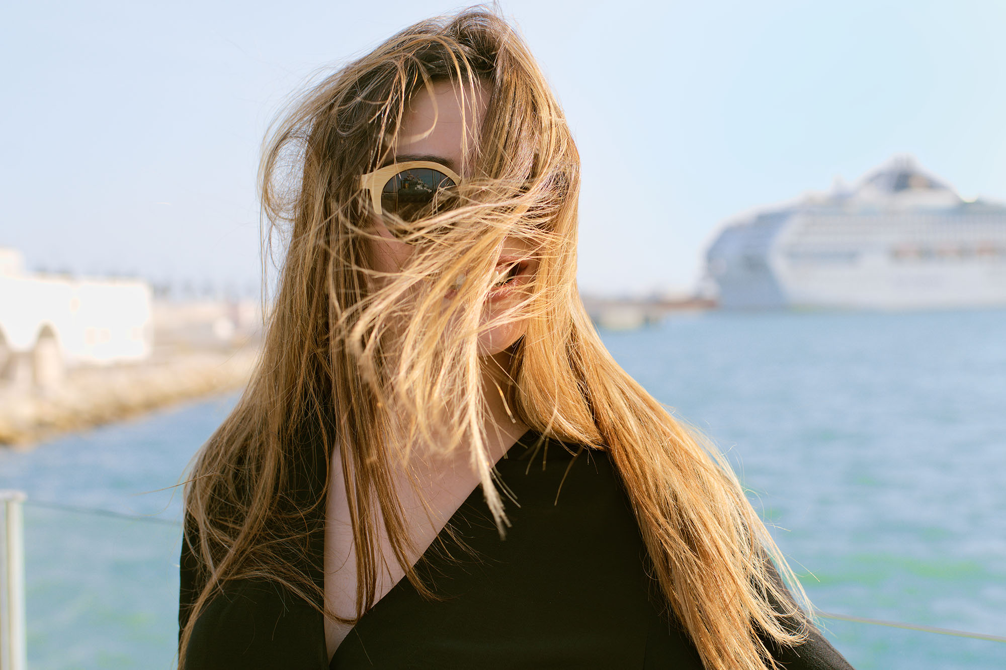 Head portrait of a beautiful young woman with her hair blown by the wind in front of the sea