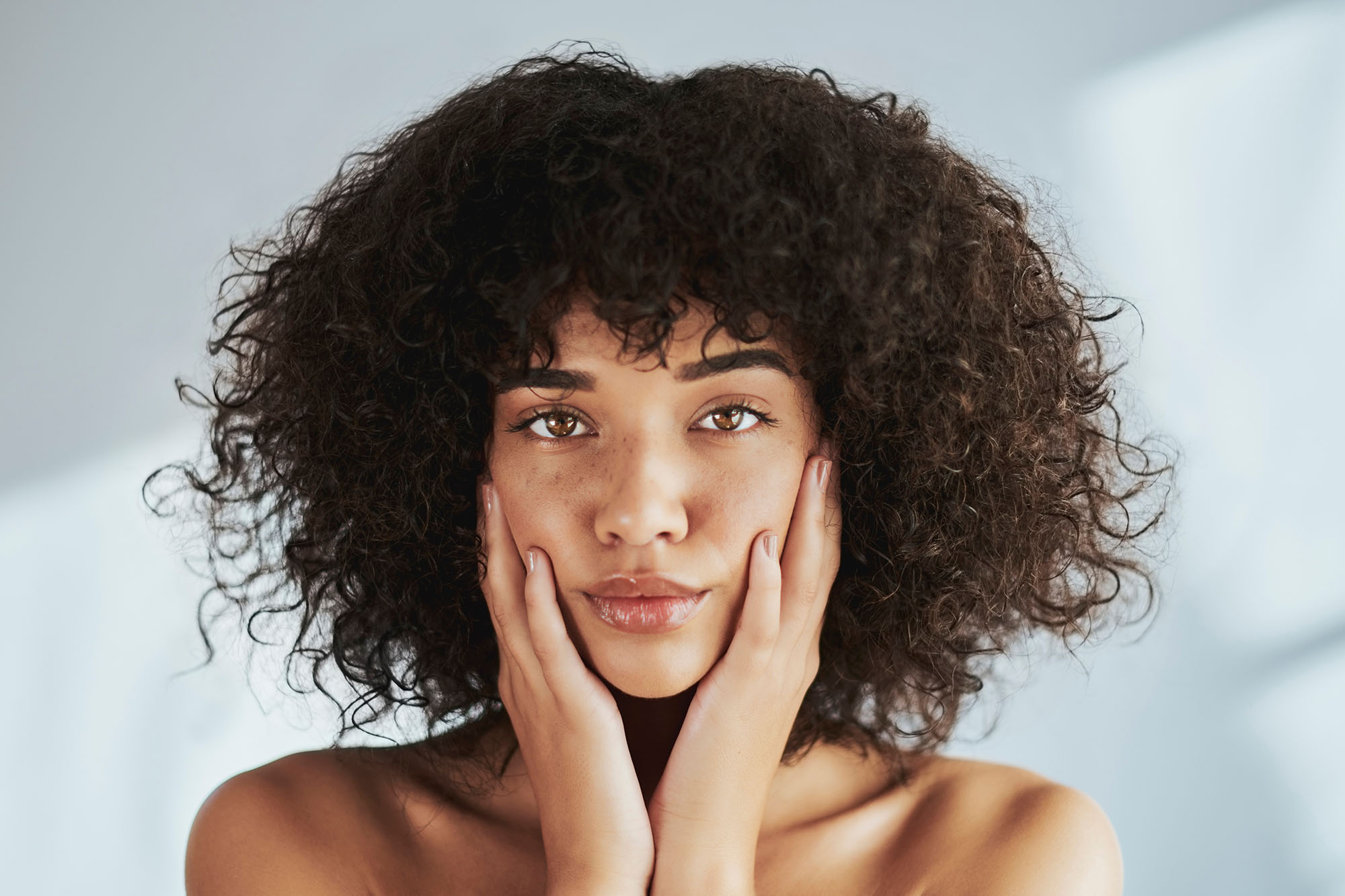 Portrait, beauty and facial with a black woman in studio to promote natural skincare or treatment. Face, skin and wellness with an attractive young female touching her cheeks for dermatology