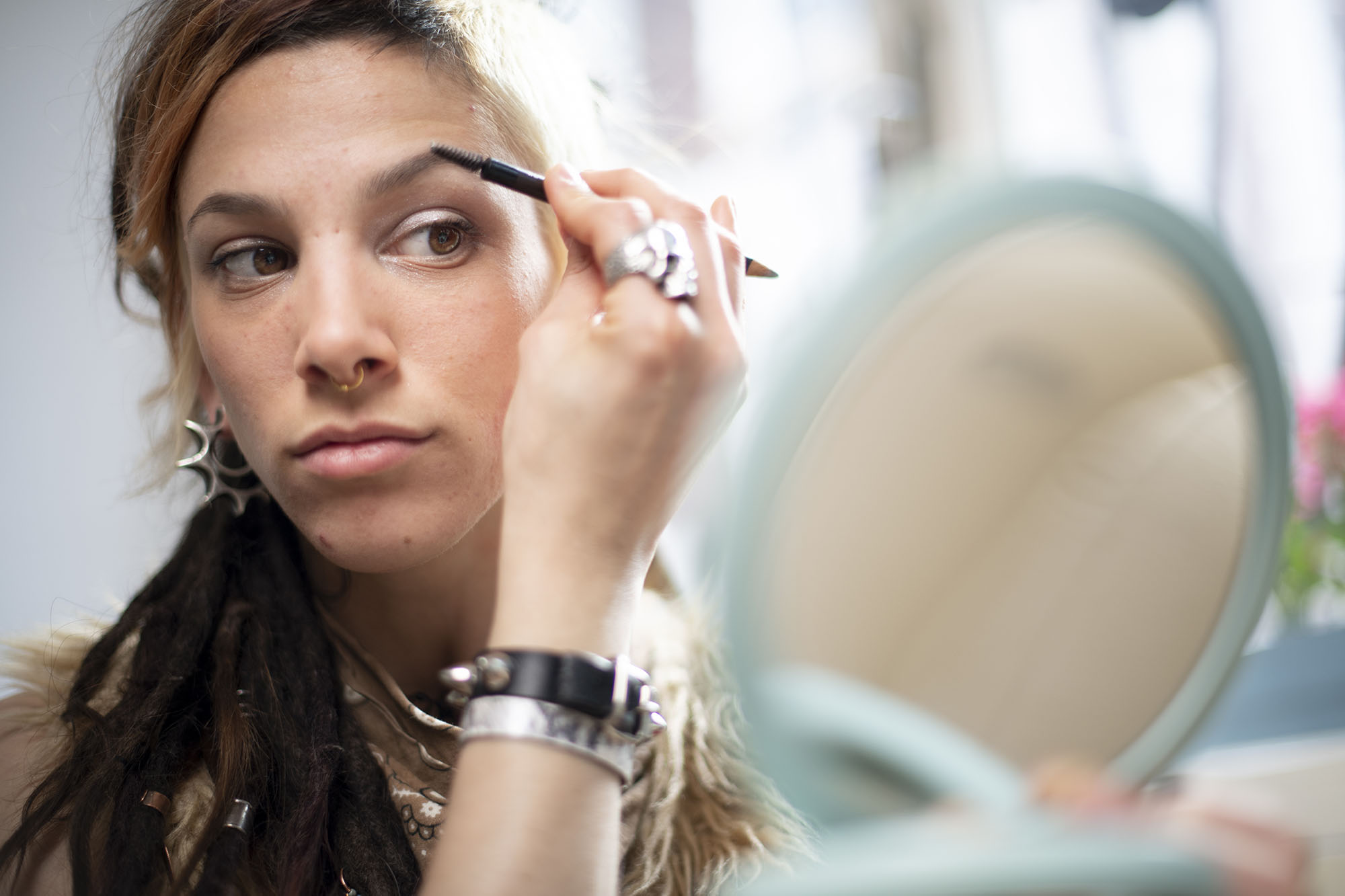 Beautiful young woman with a unique personal style putting on make-up
