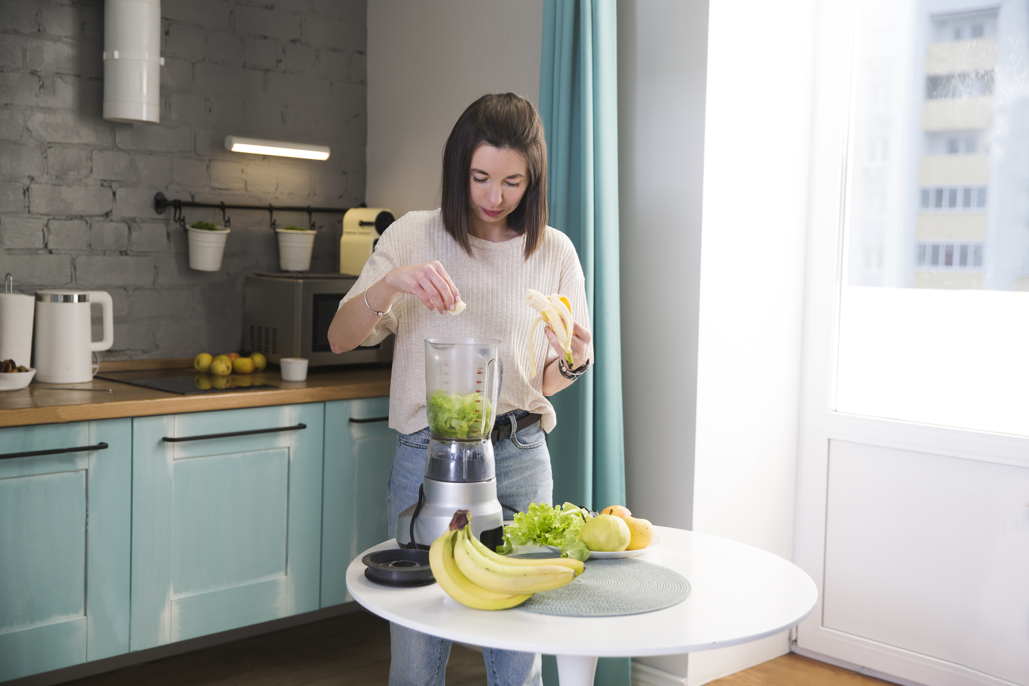 a young woman makes a smoothie in the kitchen in the morning. healthy nutrition, vegetarianism