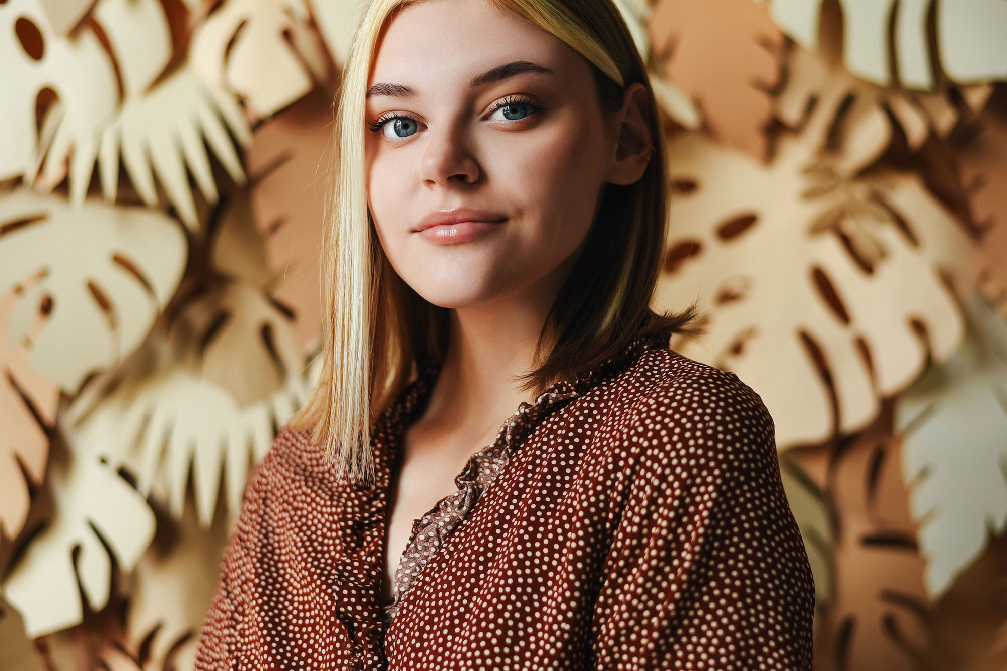Portrait of a young girl on a background with palm leaves. Tropical background. Portrait of a woman.