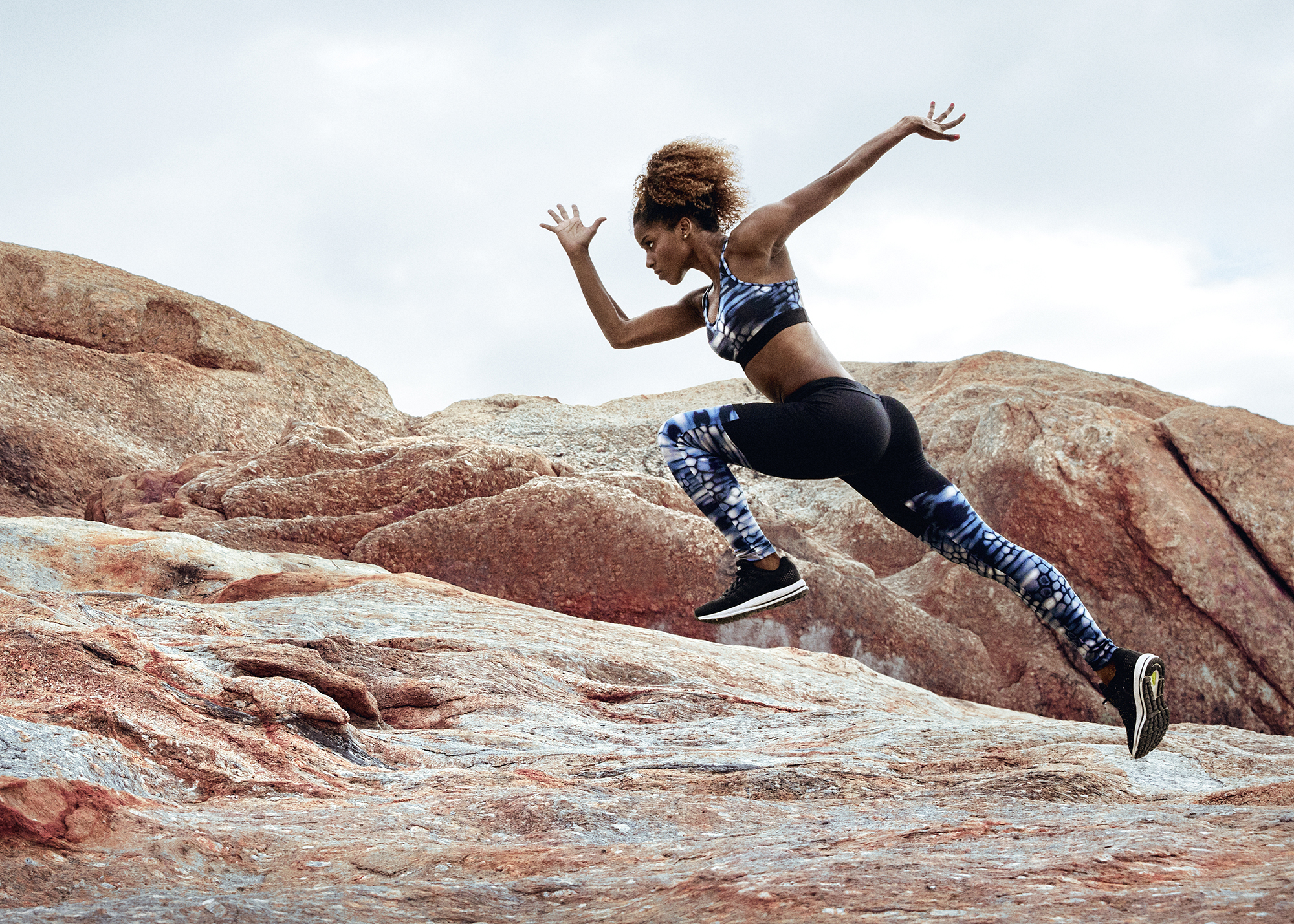 Female athlete running in a rocky environment wearing running clothes