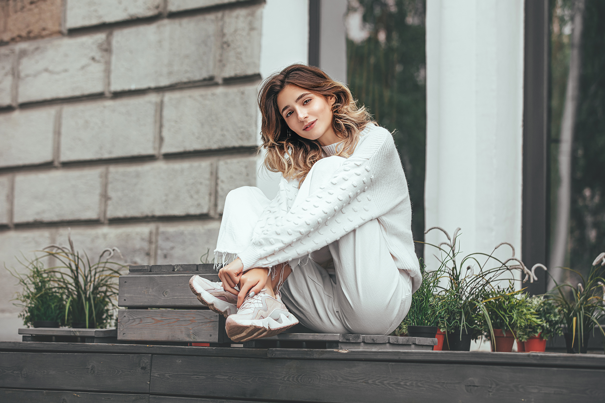 Beautiful young model girl happy and fashionable is sitting on a wooden terrace