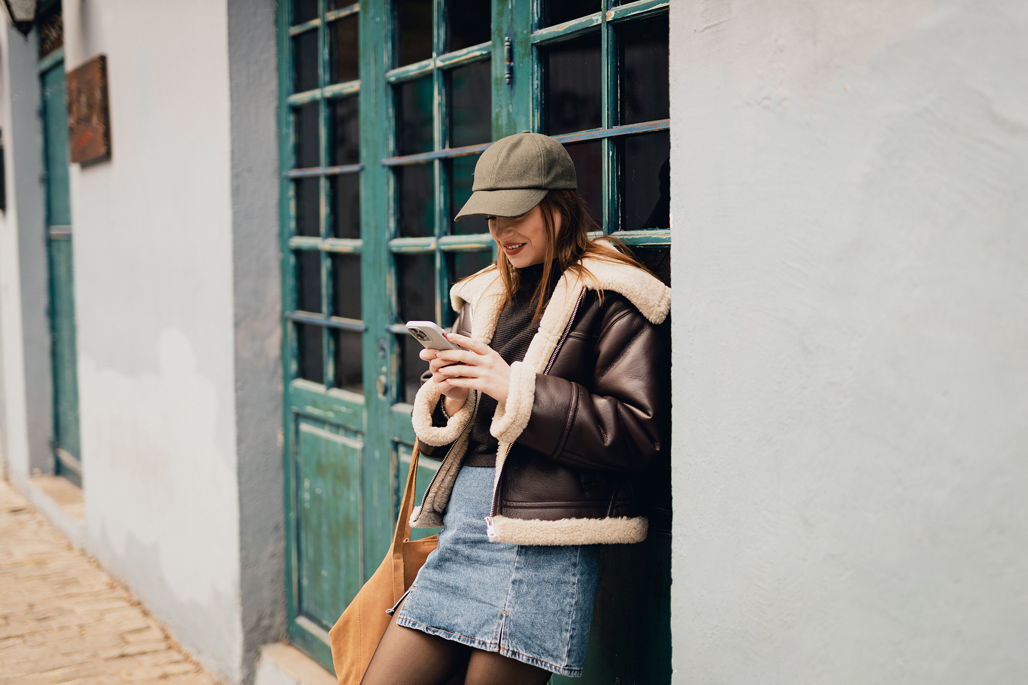 Smiling young woman using a smartphone in the city street on a lovely autumn day