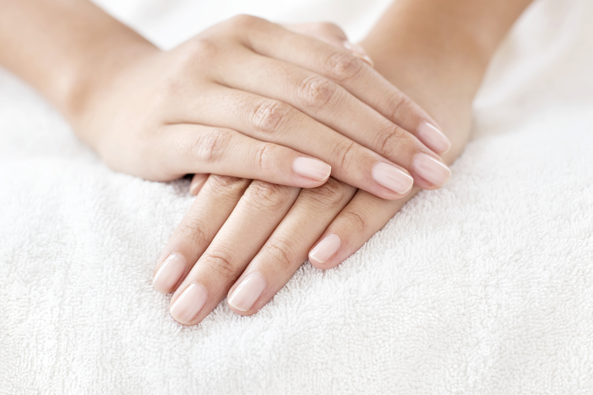 Young woman with hands resting on white towel.