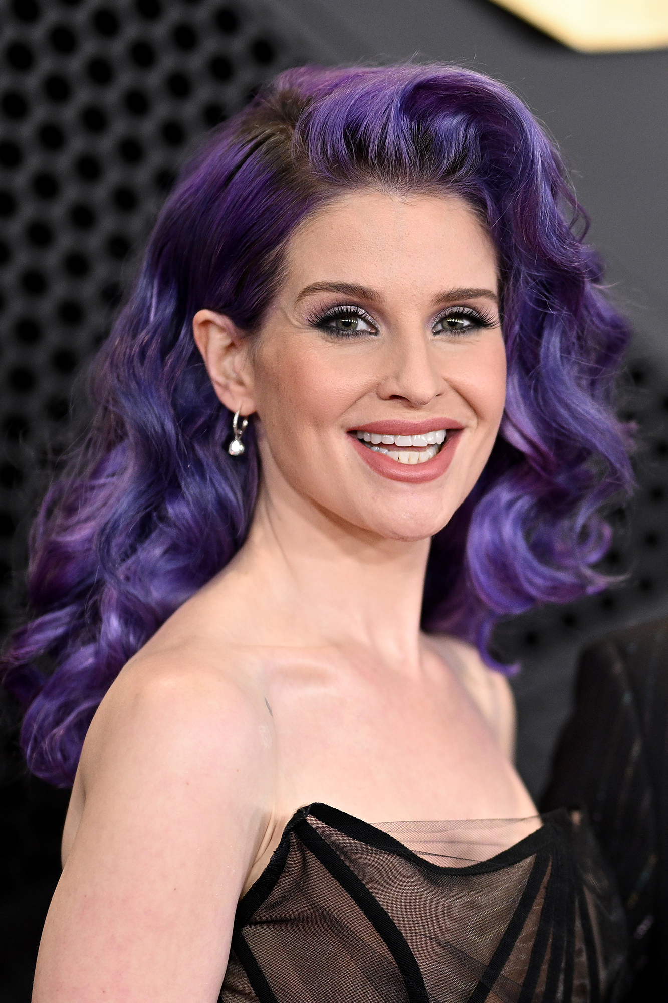 Kelly Osbourne with Curly Purple Hair Smiling and Looking at Camera in Black Top Sheer Dress
