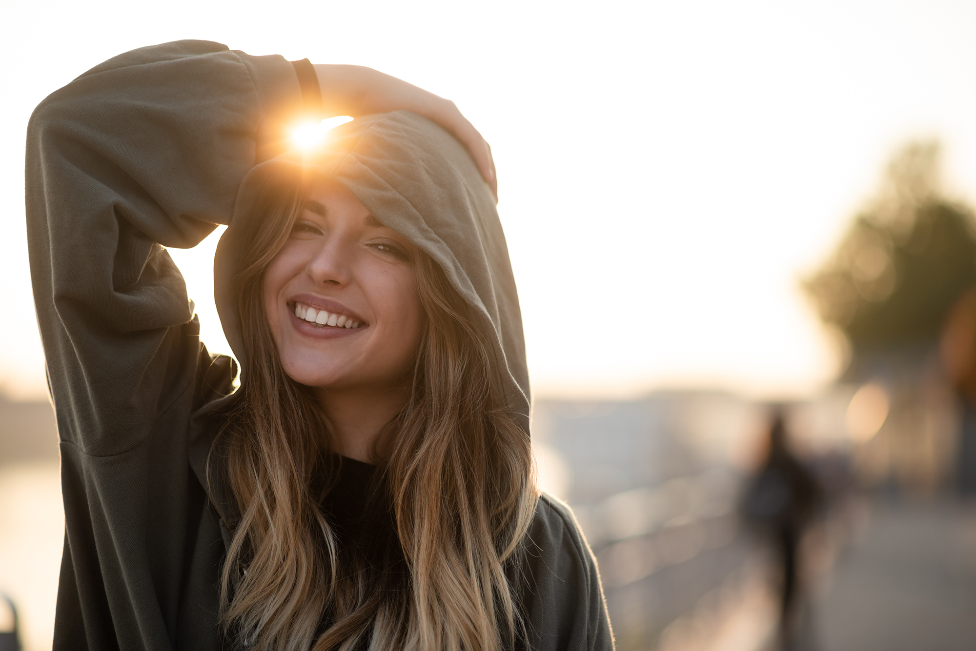 Playful teen woman outdoors in hooded sweatshirt