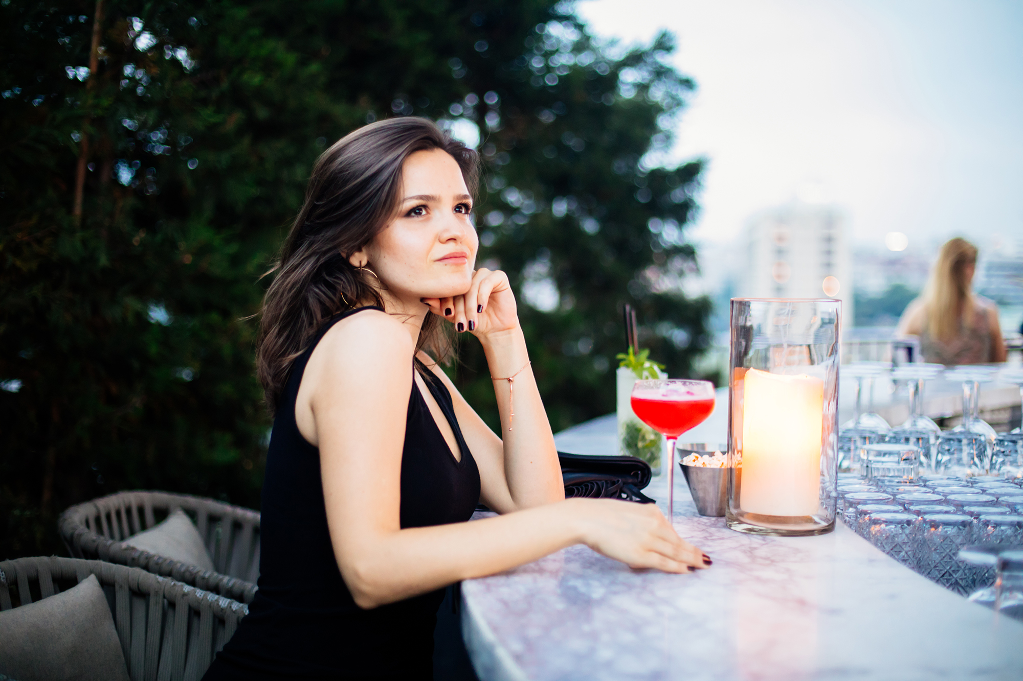 Beautiful woman drinking pink cocktail at roof bar