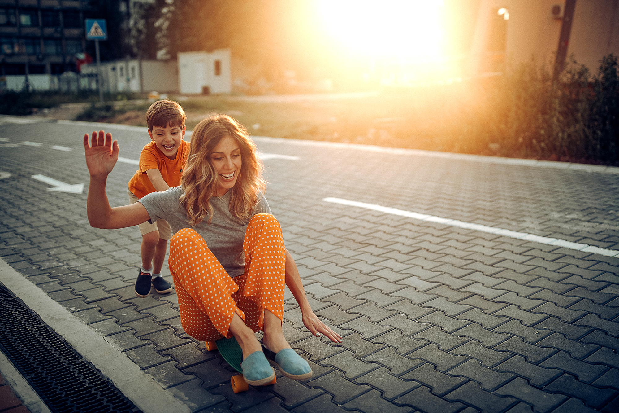 Mother and son playing in public park, driving skateboard