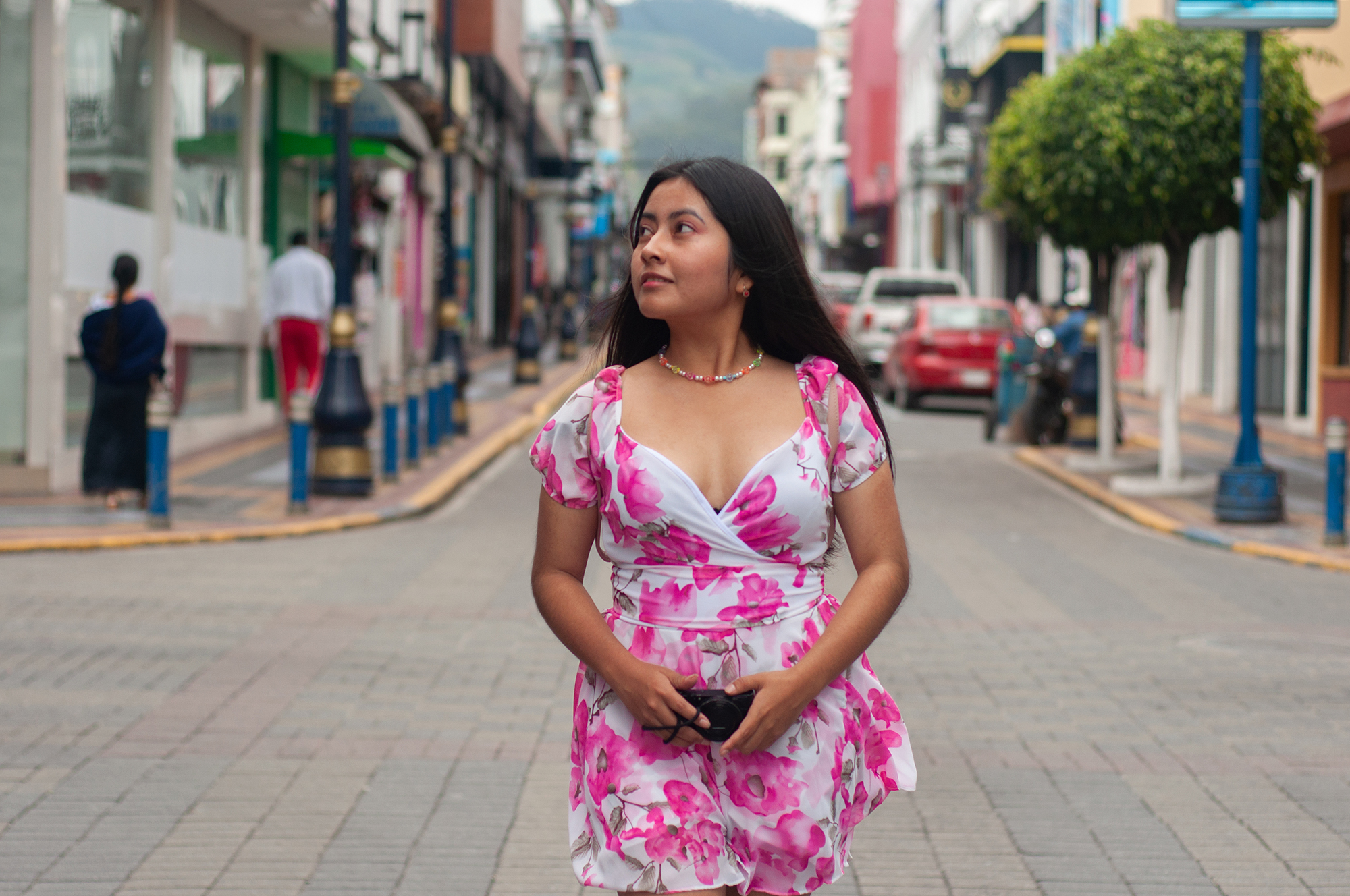 A pensive young woman in a vibrant floral dress