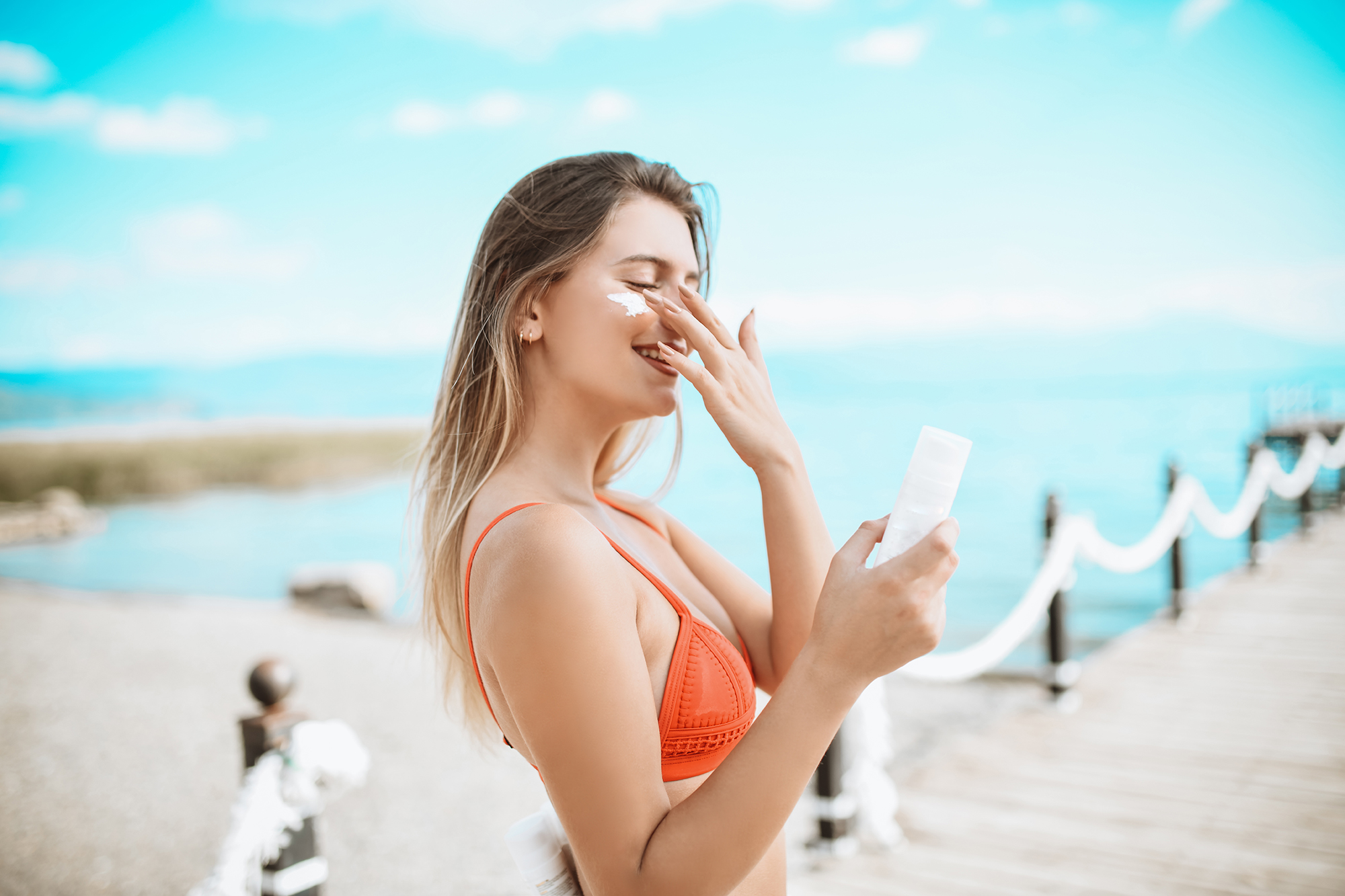 Smiling Female Beauty And Her Favorite Sunscreen At The Beach