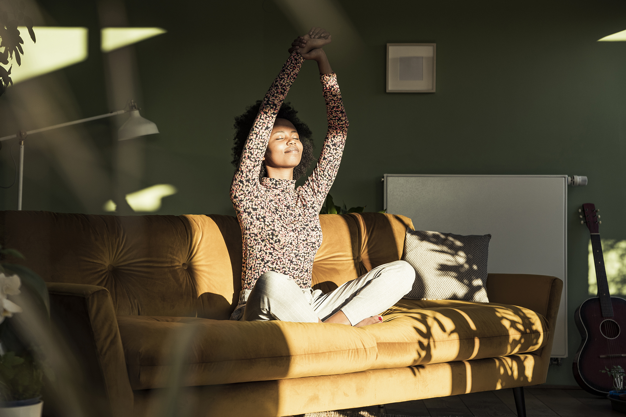 Woman with hands raised sitting on sofa at home