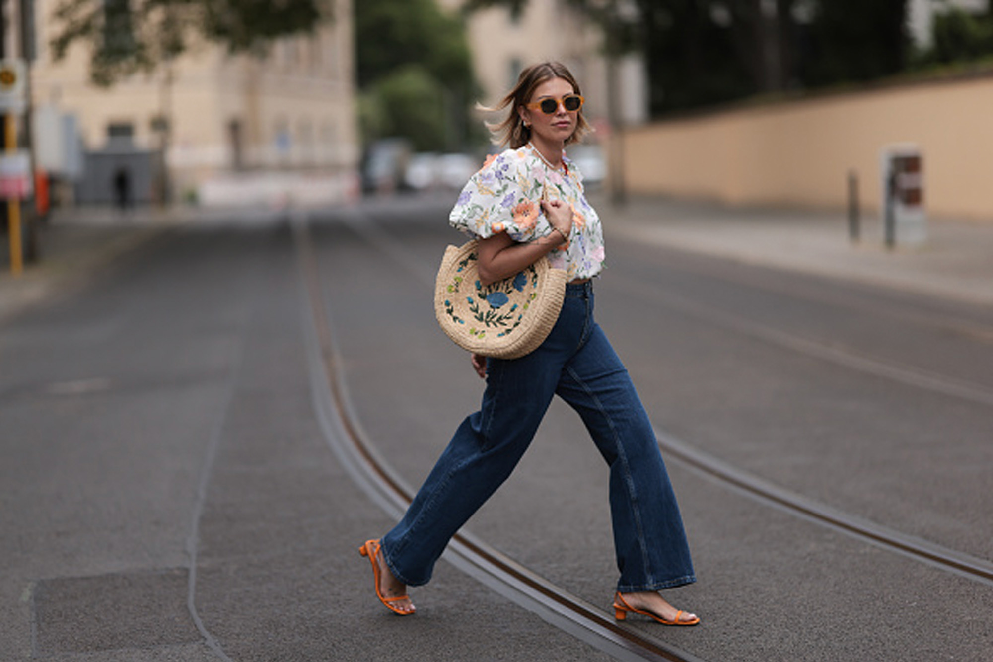 woman wearing jeans, floral blouse and woven bag
