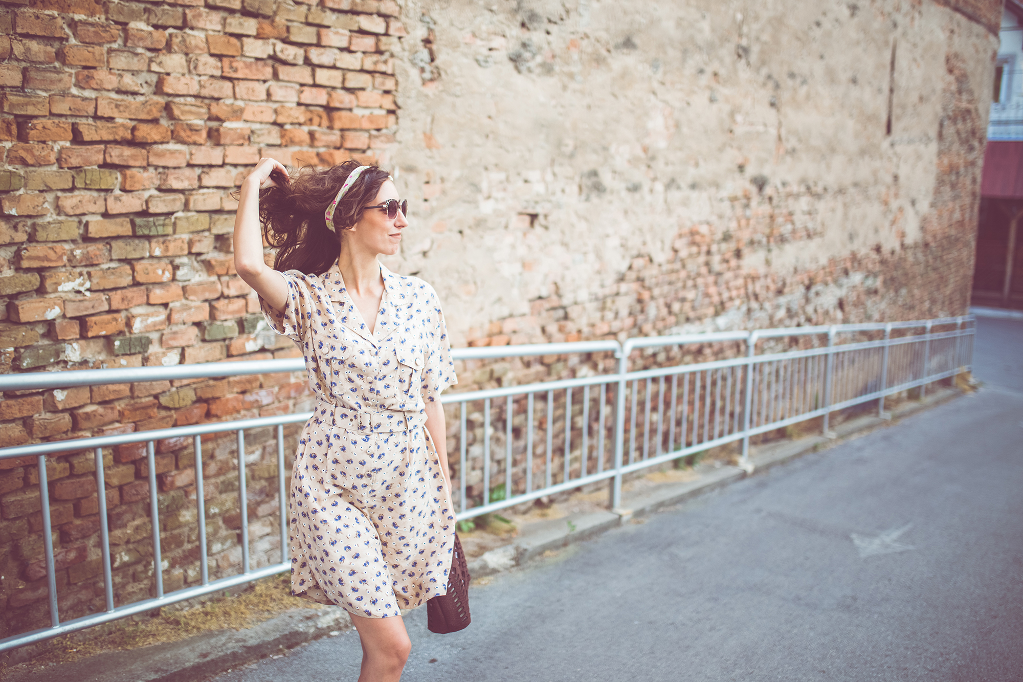 Woman enjoying outside and walking near the old brick wall.