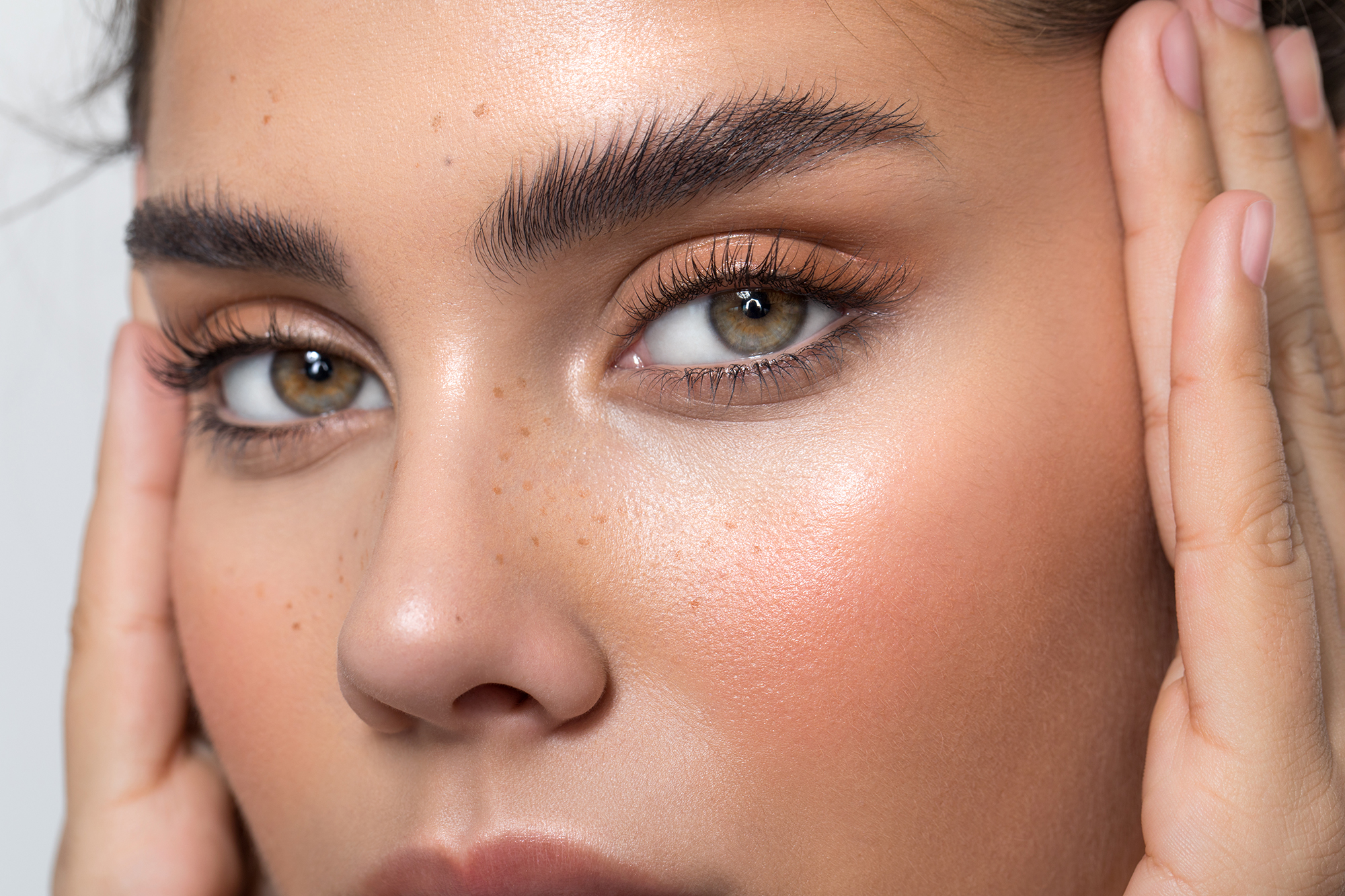 Closeup studio shot of a beautiful woman with freckles skin posing against a grey background