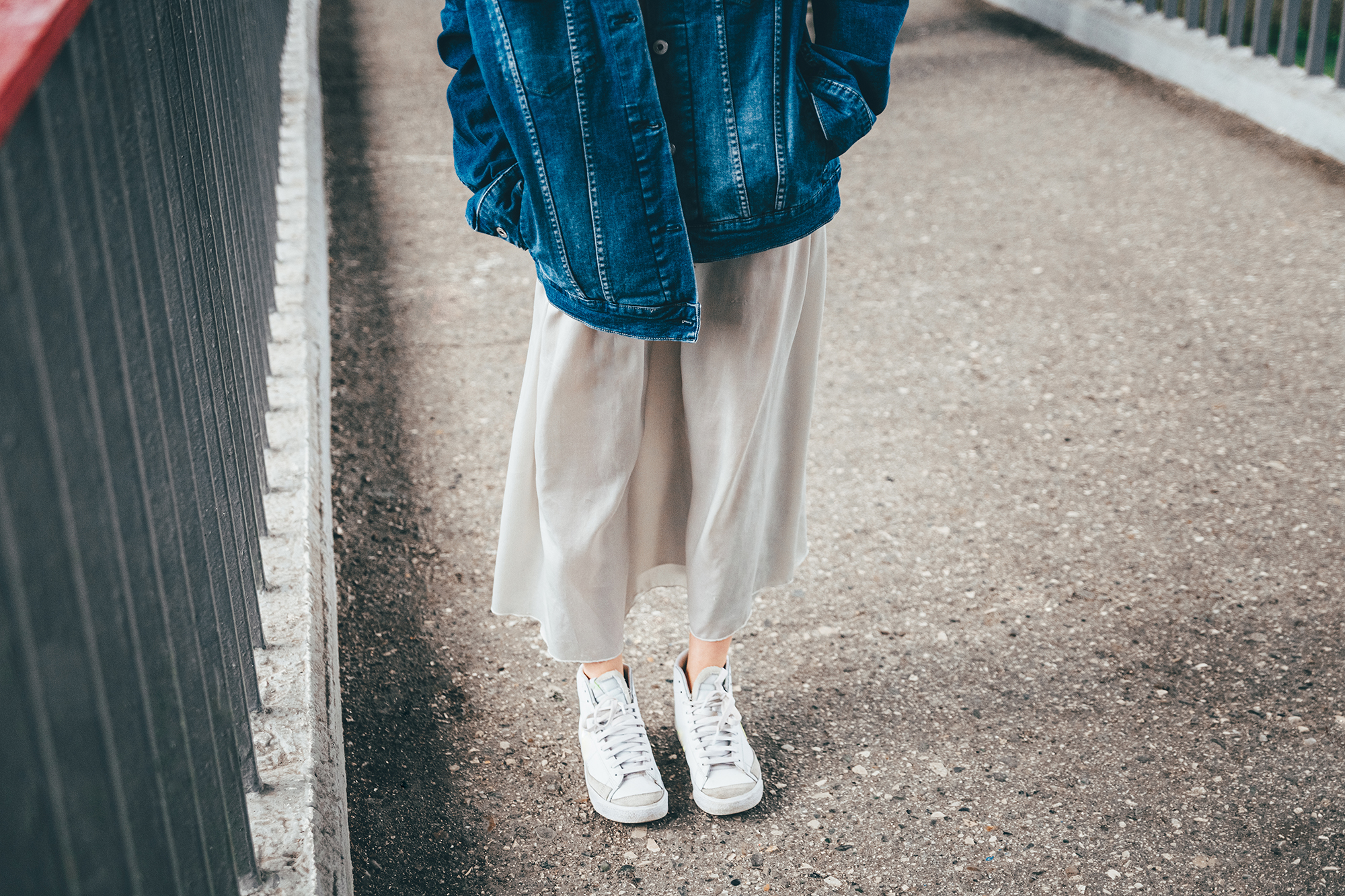 Cropped photo of a girl dressed in a denim jacket and skirt on a city street