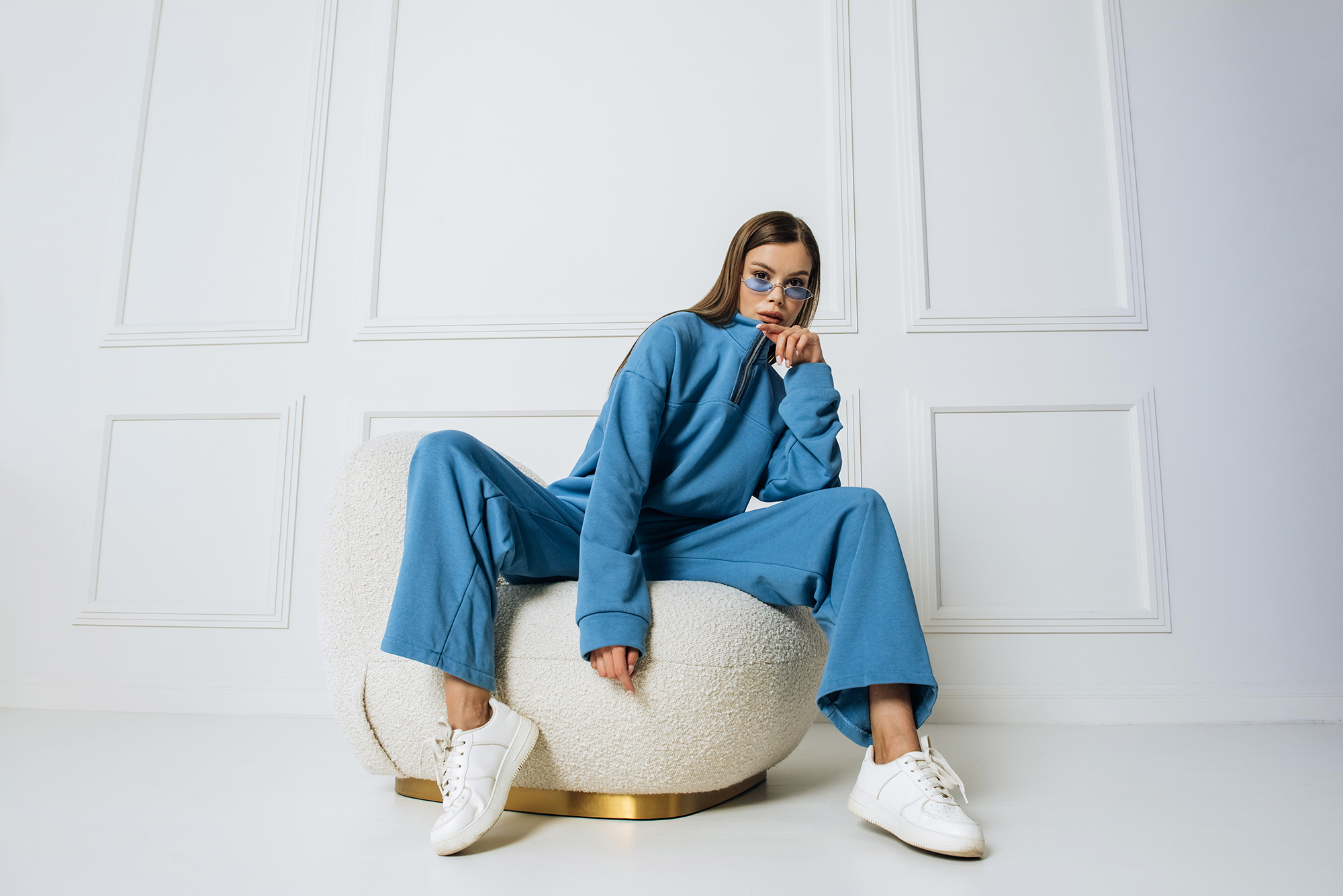Fashion model woman sitting in a chair posing in a new collection of sportswear.