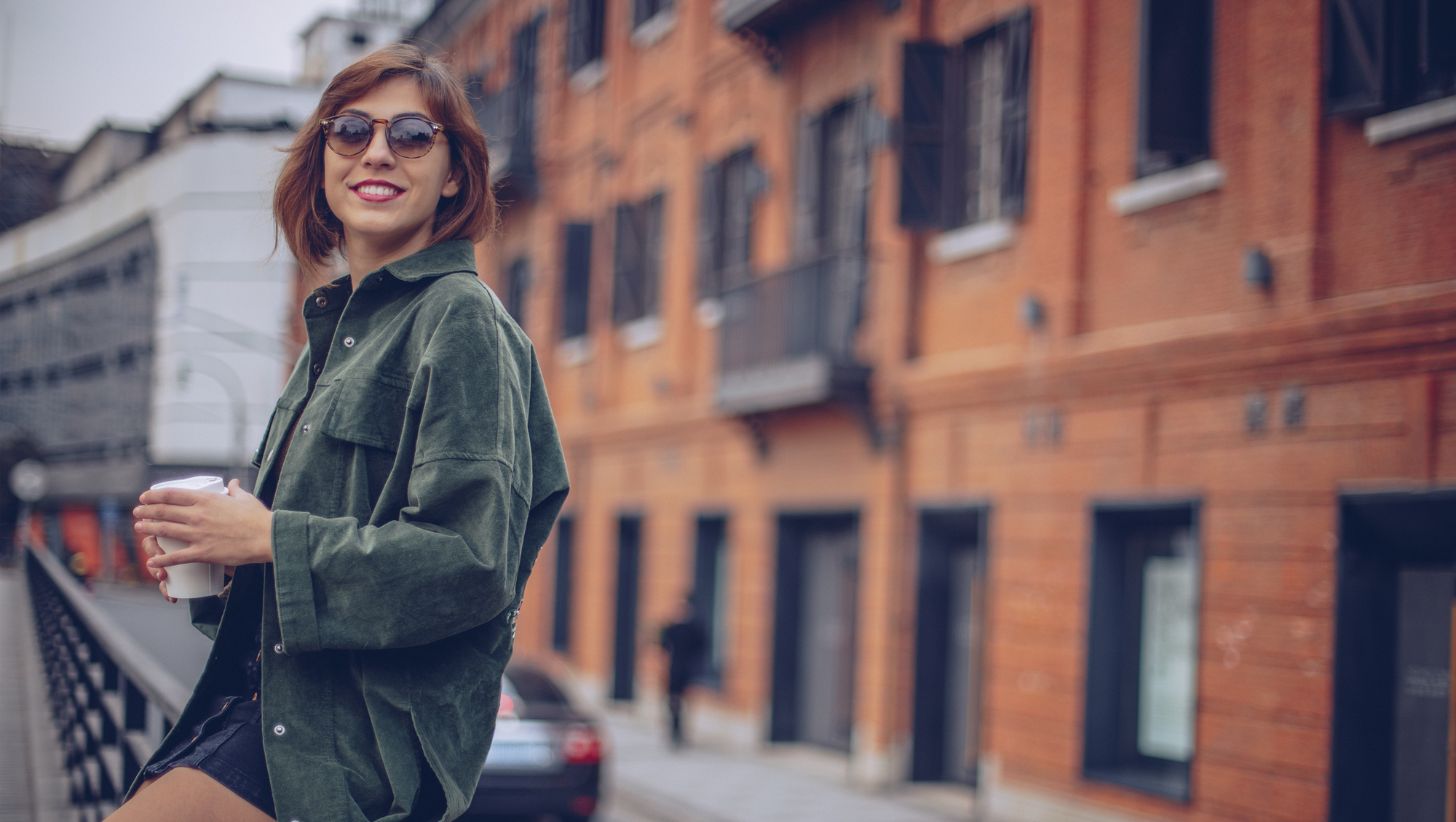 woman sitting on a railing drinking coffee