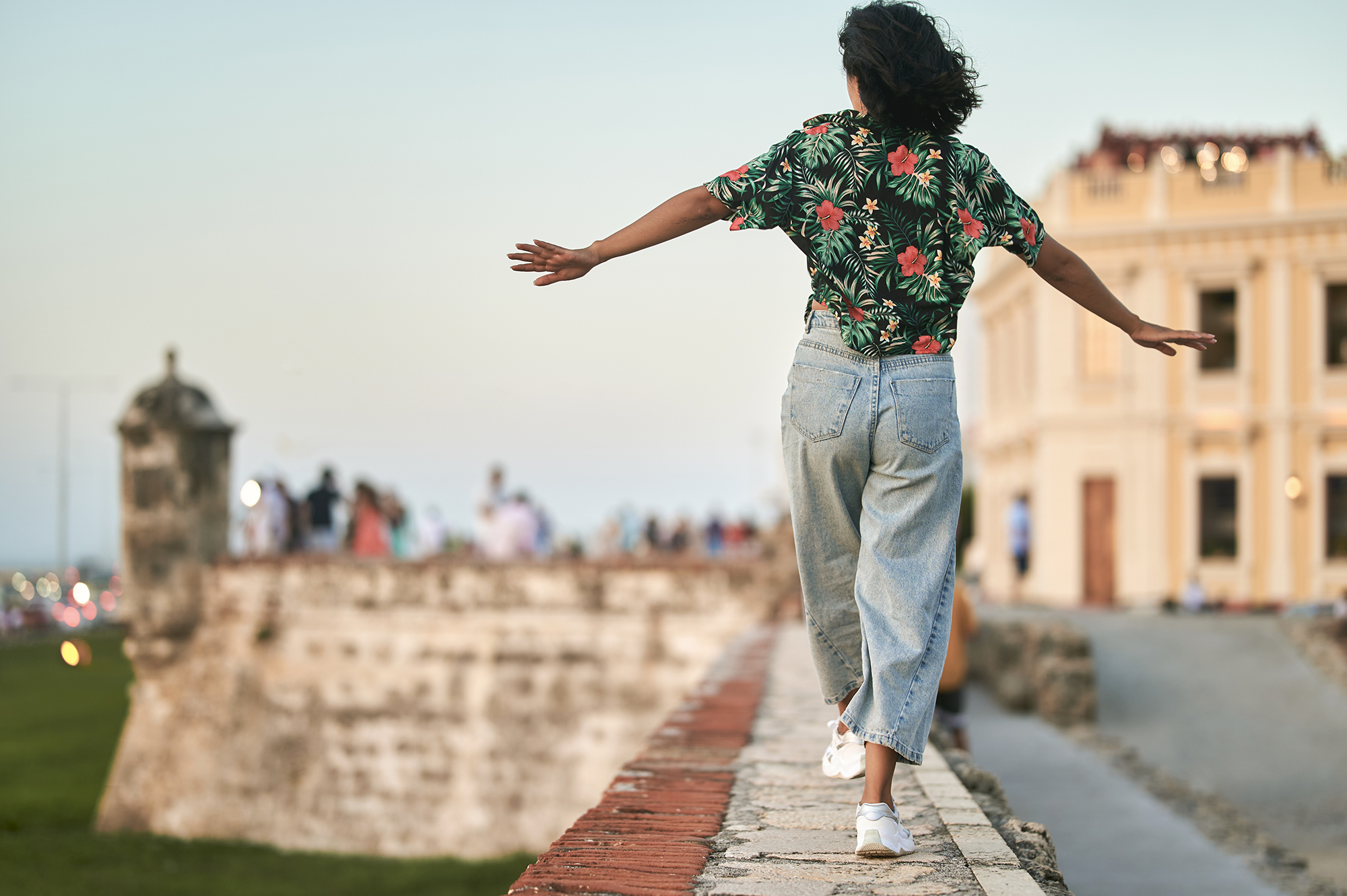 Woman walking on wall seen from behind in Cartagena, Colombia
