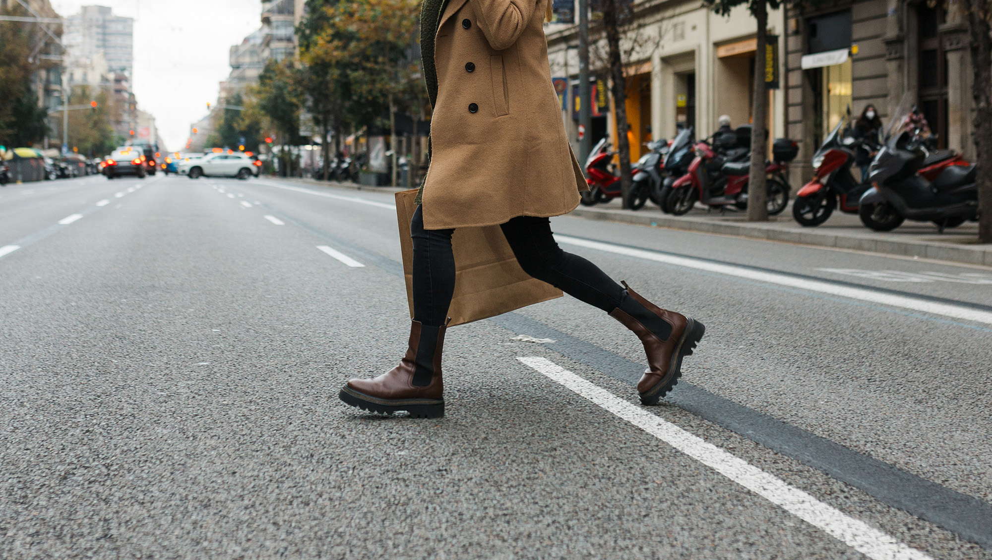 Happy woman on a shopping day in the city's shopping district, looking at the camera with a big smile. Walking down the street on a cloudy autumn day.