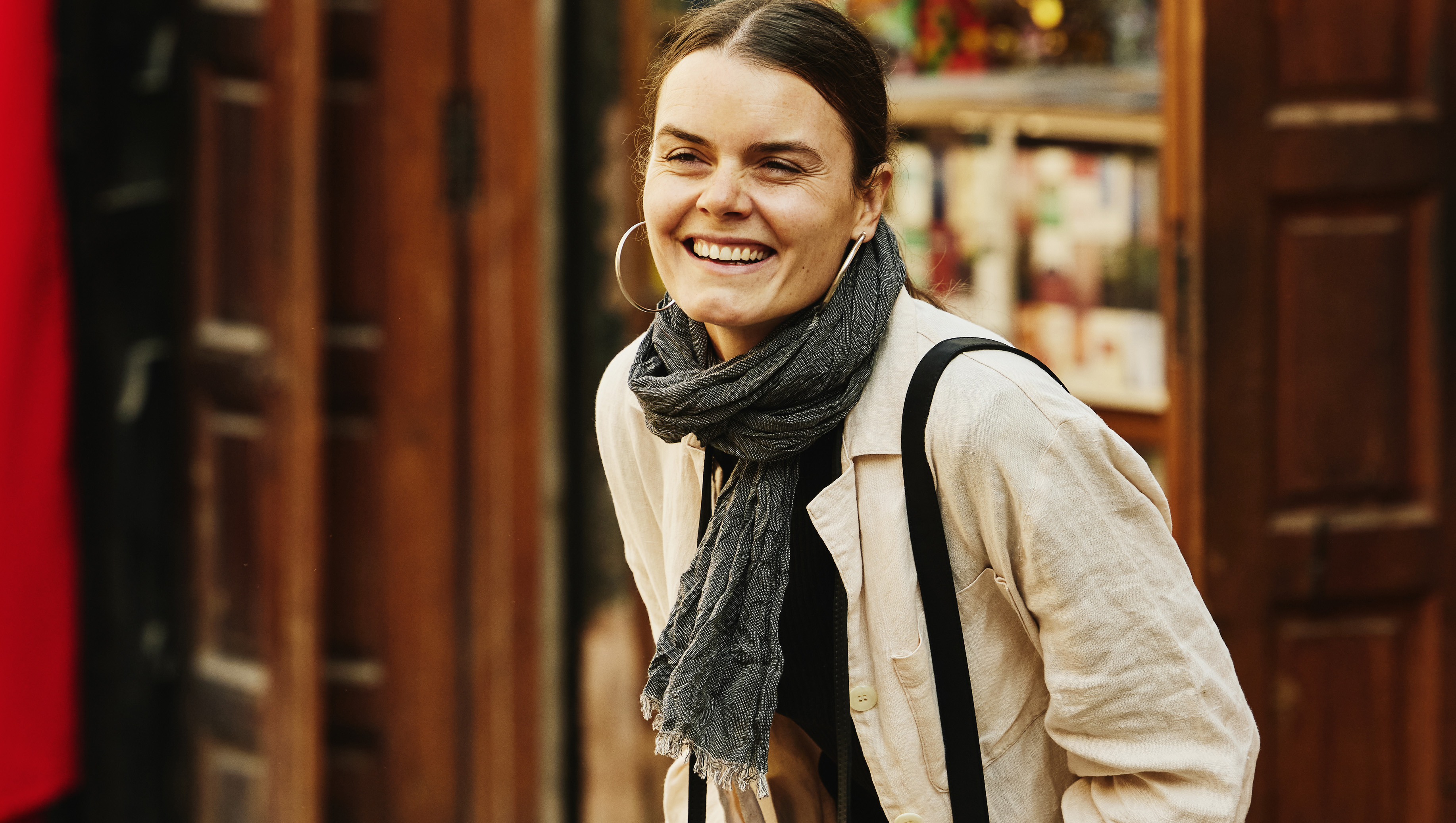 Wide shot of solo female traveler laughing while taking photographs in the medina of Marrakech during vacation in Morocco