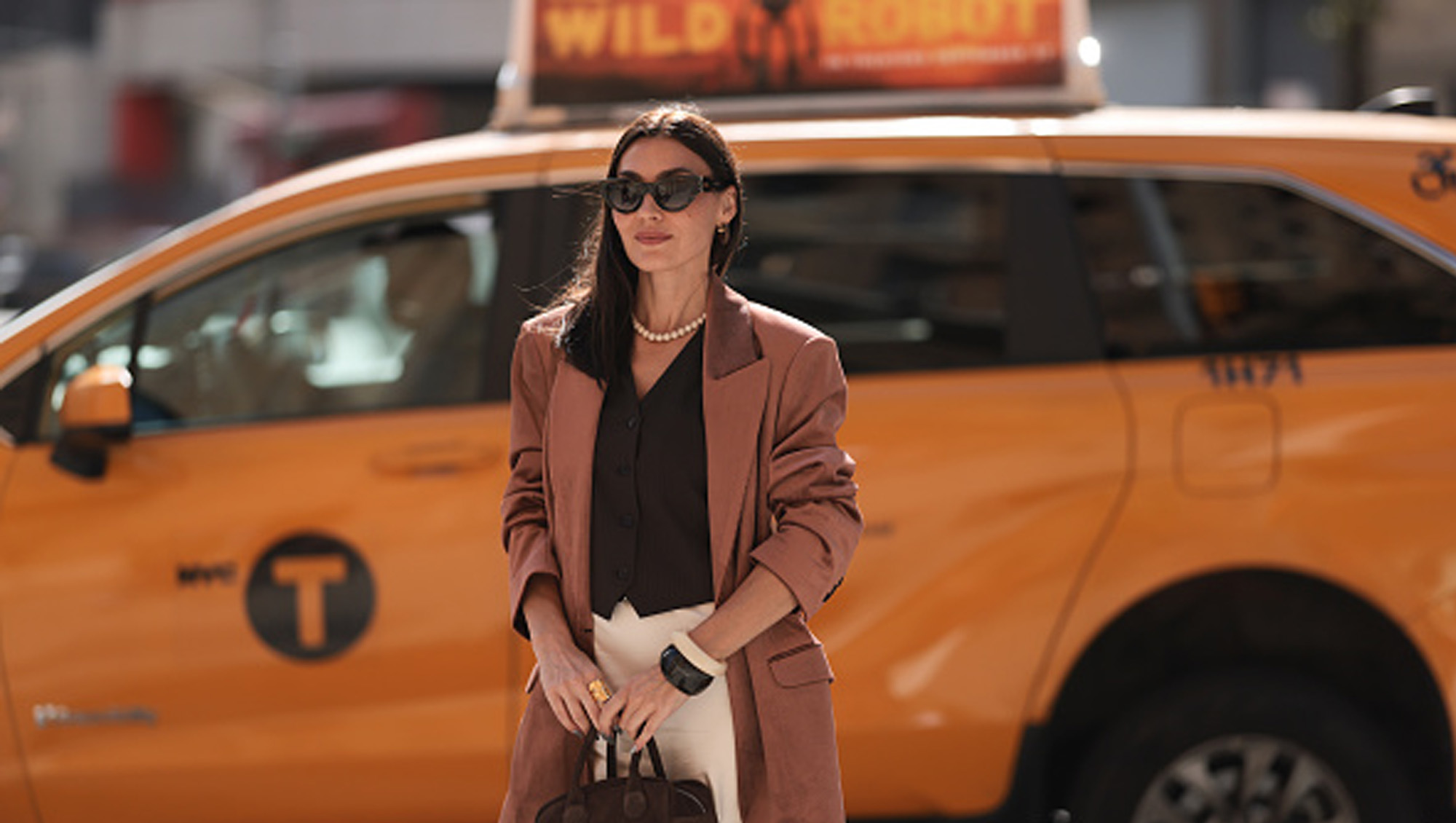 woman in chic outfit next to yellow taxi