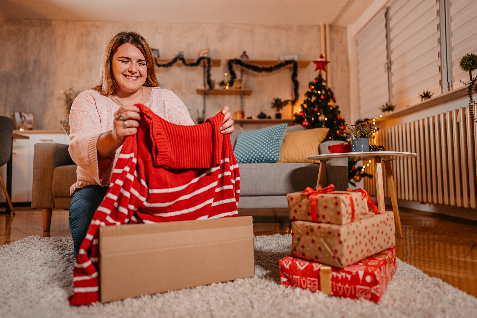 Young Plus Size Woman Unwrapping A New Sweater For Christmas