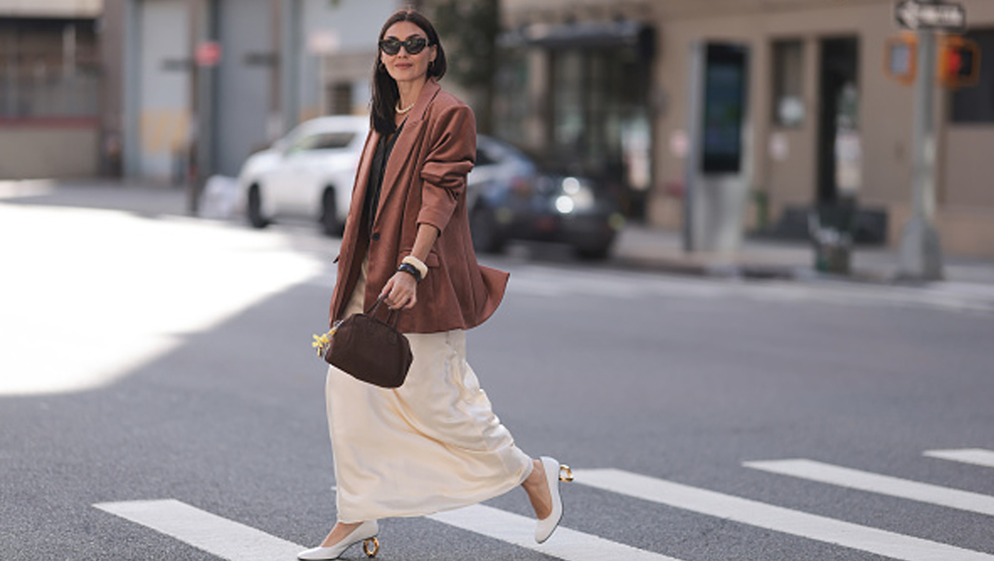 woman wearing brown blazer and cream skirt on street