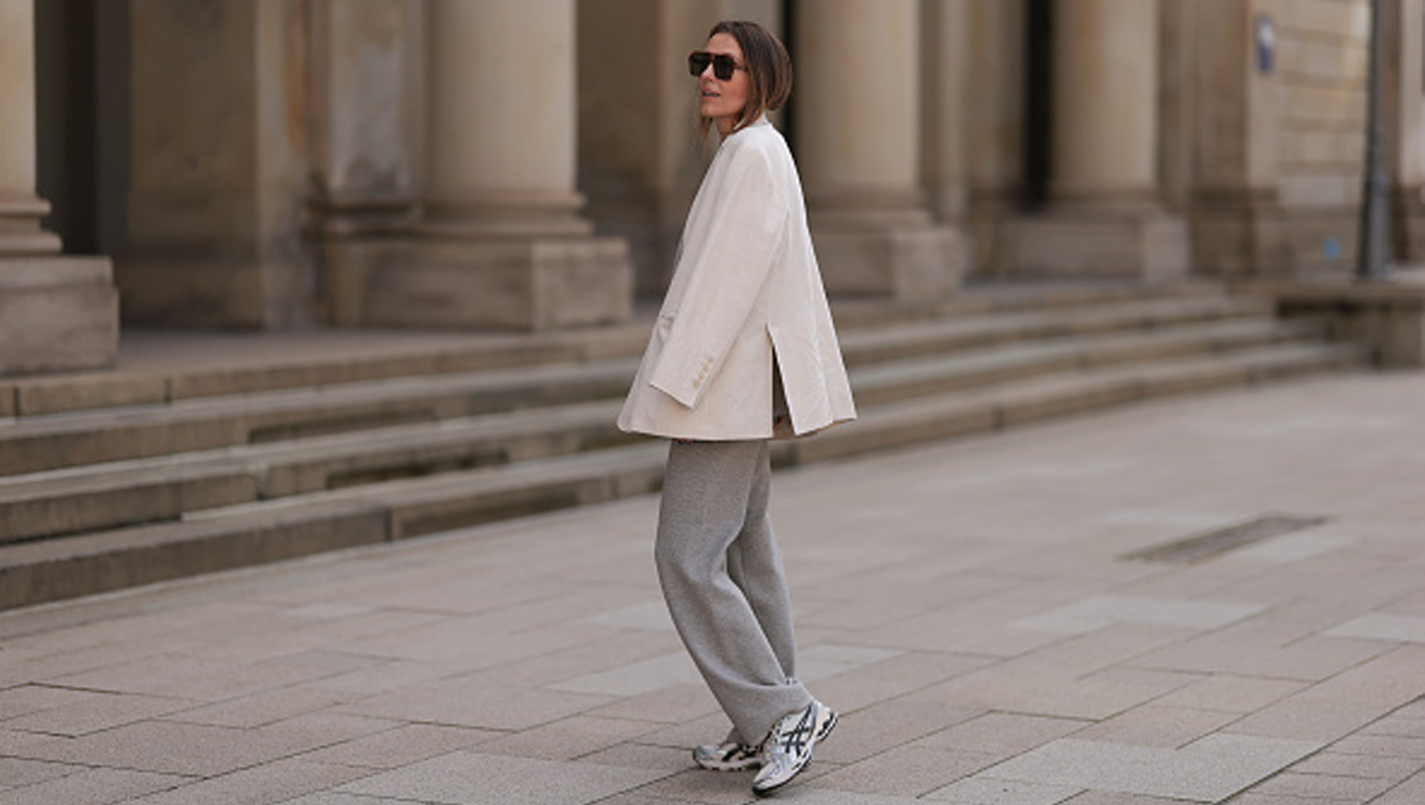 woman wearing sneakers, white blazer and gray pants