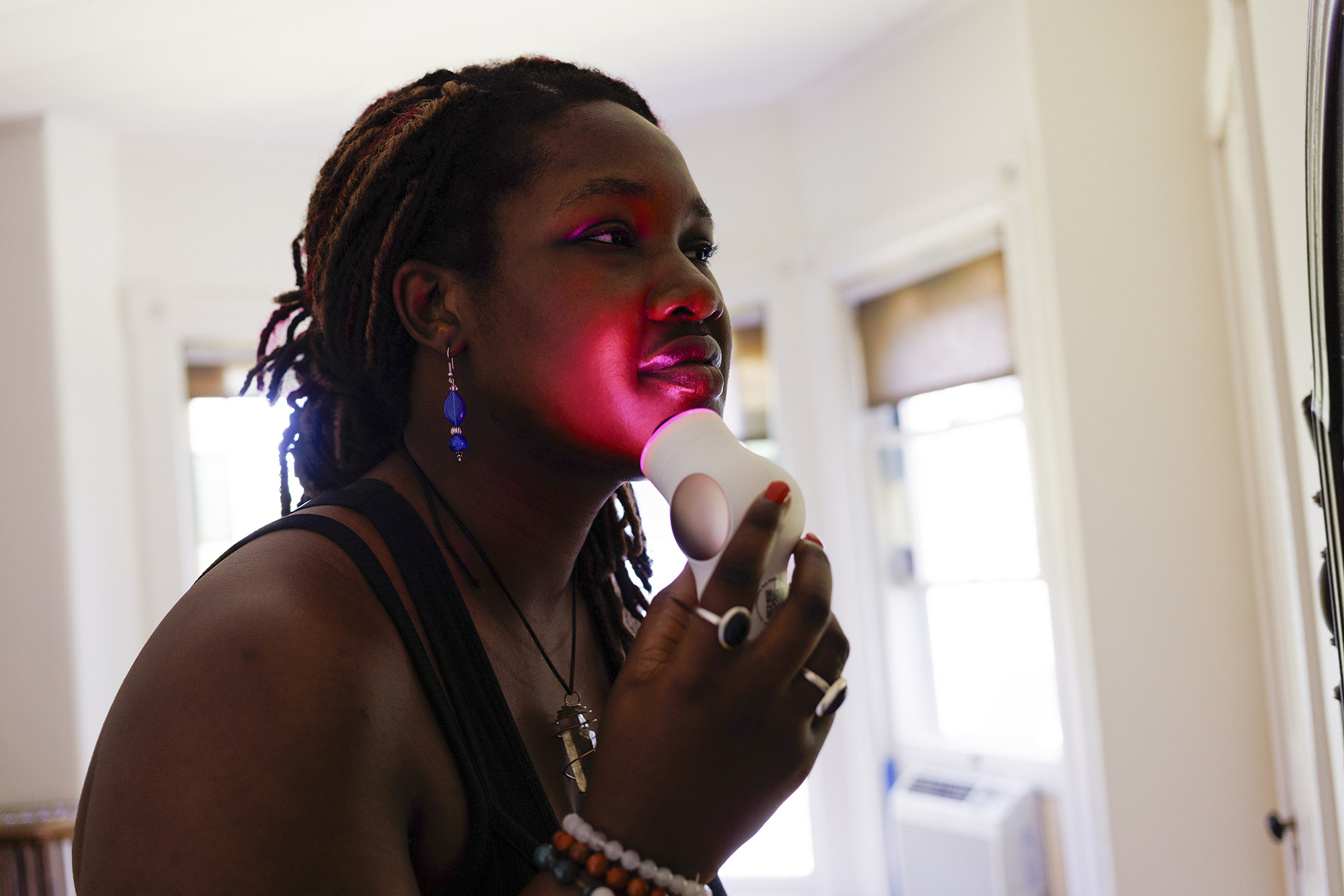 Young woman using red light therapy on face