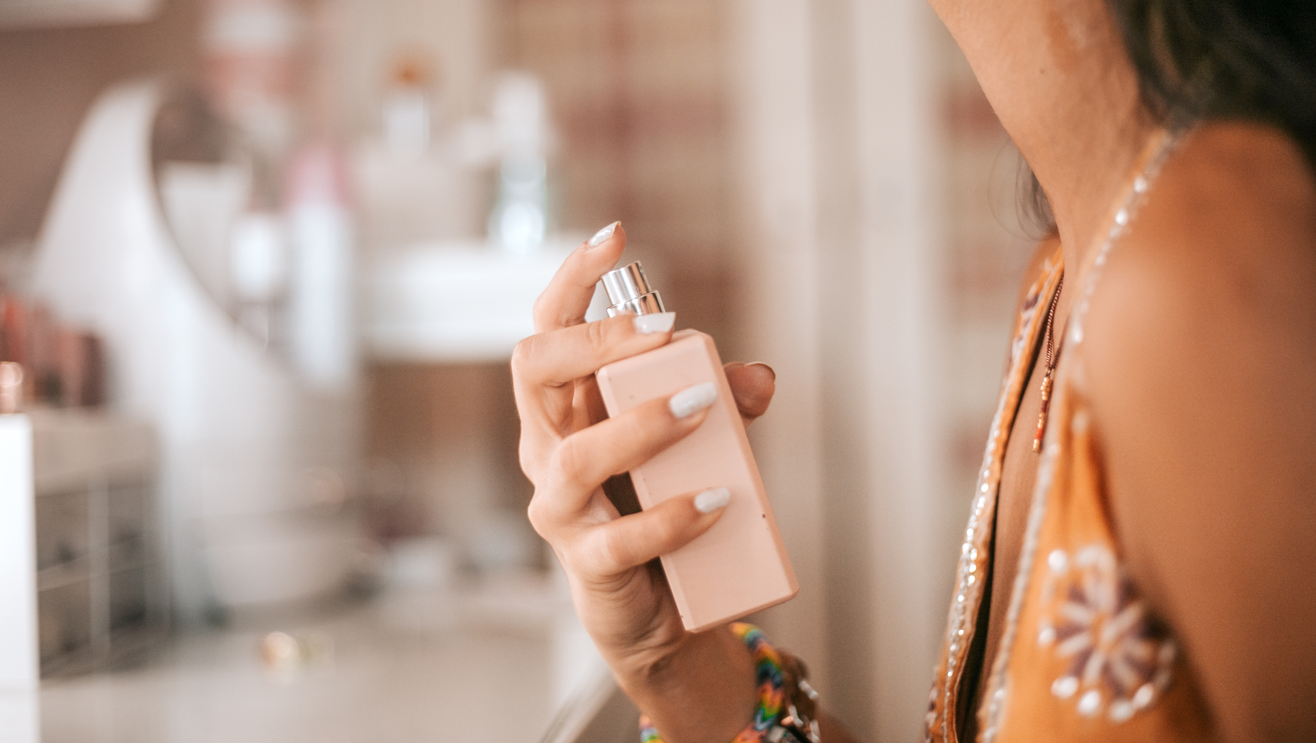 closeup woman spraying perfume on wrist