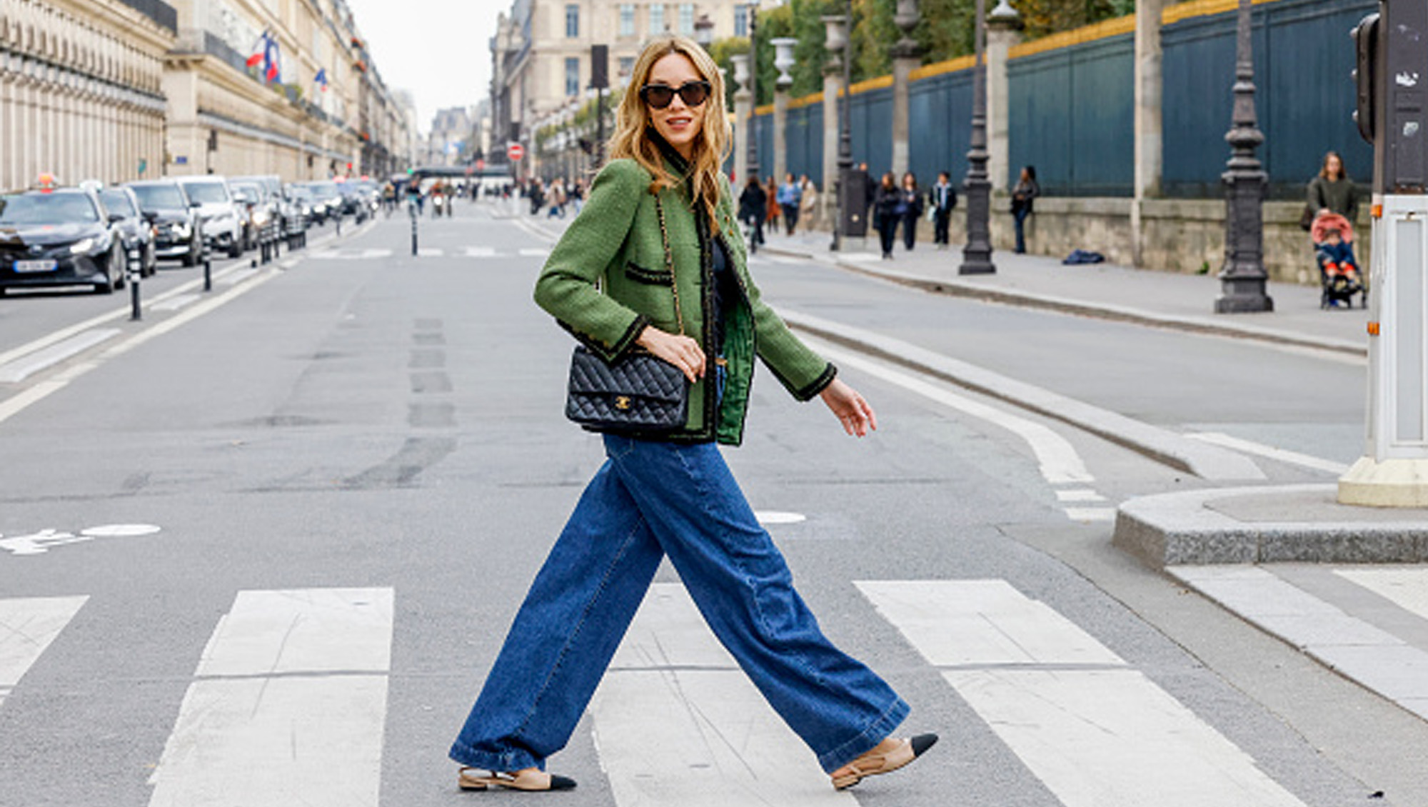 woman wearing jeans walking across the street