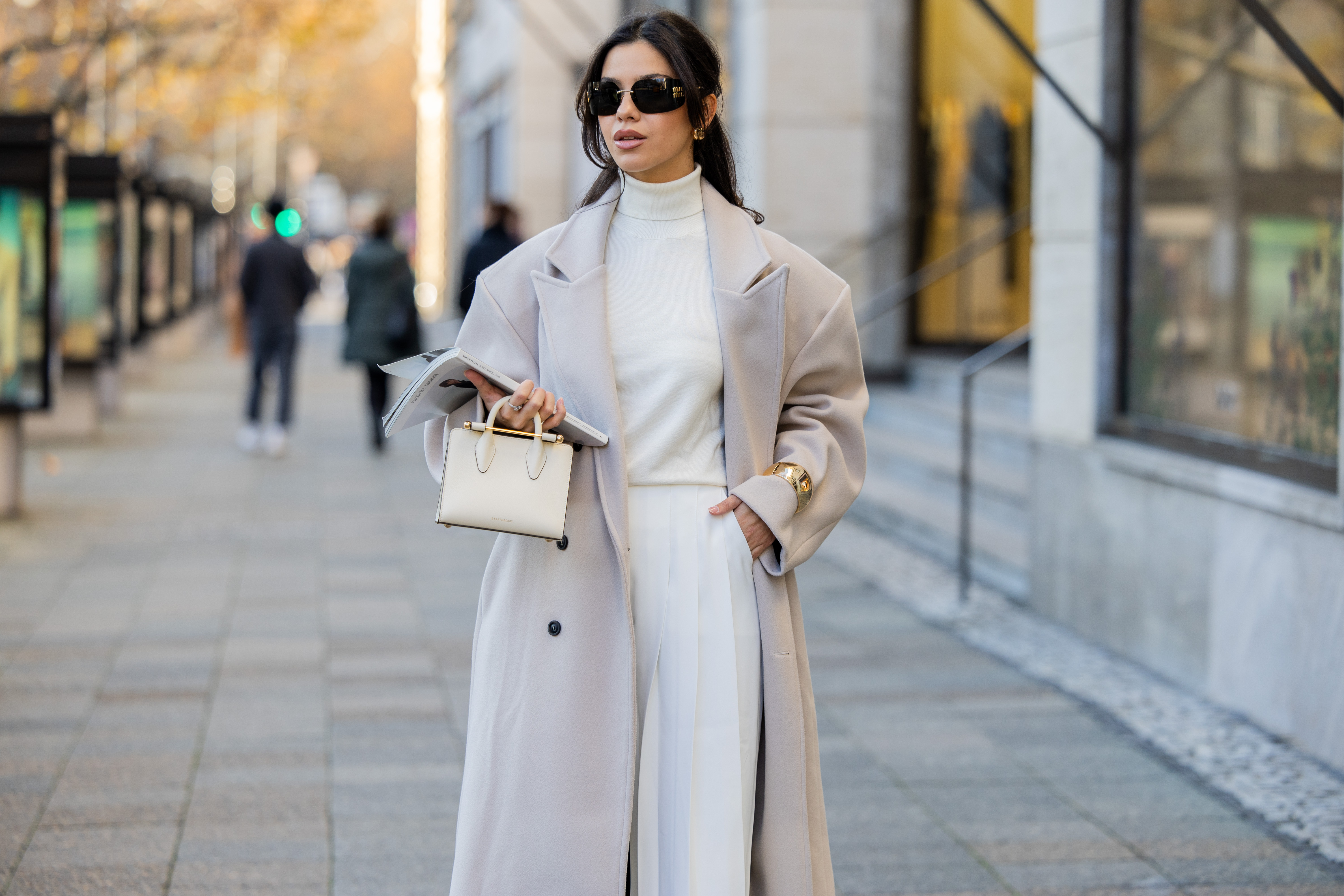 Bella Emar wears oversized grey double breasted sourceunknown coat, creme white turtleneck top Zara, white wide leg pants Frankie Shop, strathberry bag on November 30, 2024 in Berlin, Germany.