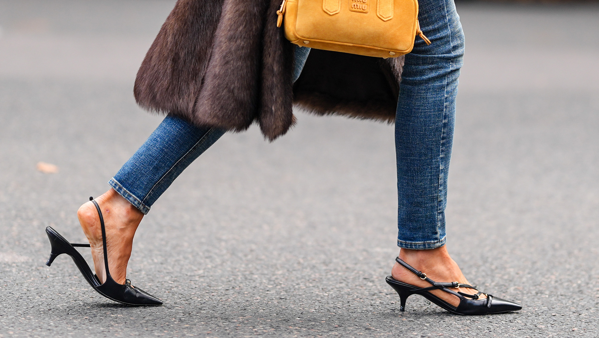 PARIS, FRANCE - OCTOBER 01: Caroline Daur wears a bright orange Miu Miu leather bag, black pointed toe strappy slingback leather Miu MIu heels, outside Miu Miu, during the Paris Fashion Week Spring/Summer 2025 on October 1, 2024 in Paris, France (Photo by Edward Berthelot/Getty Images)