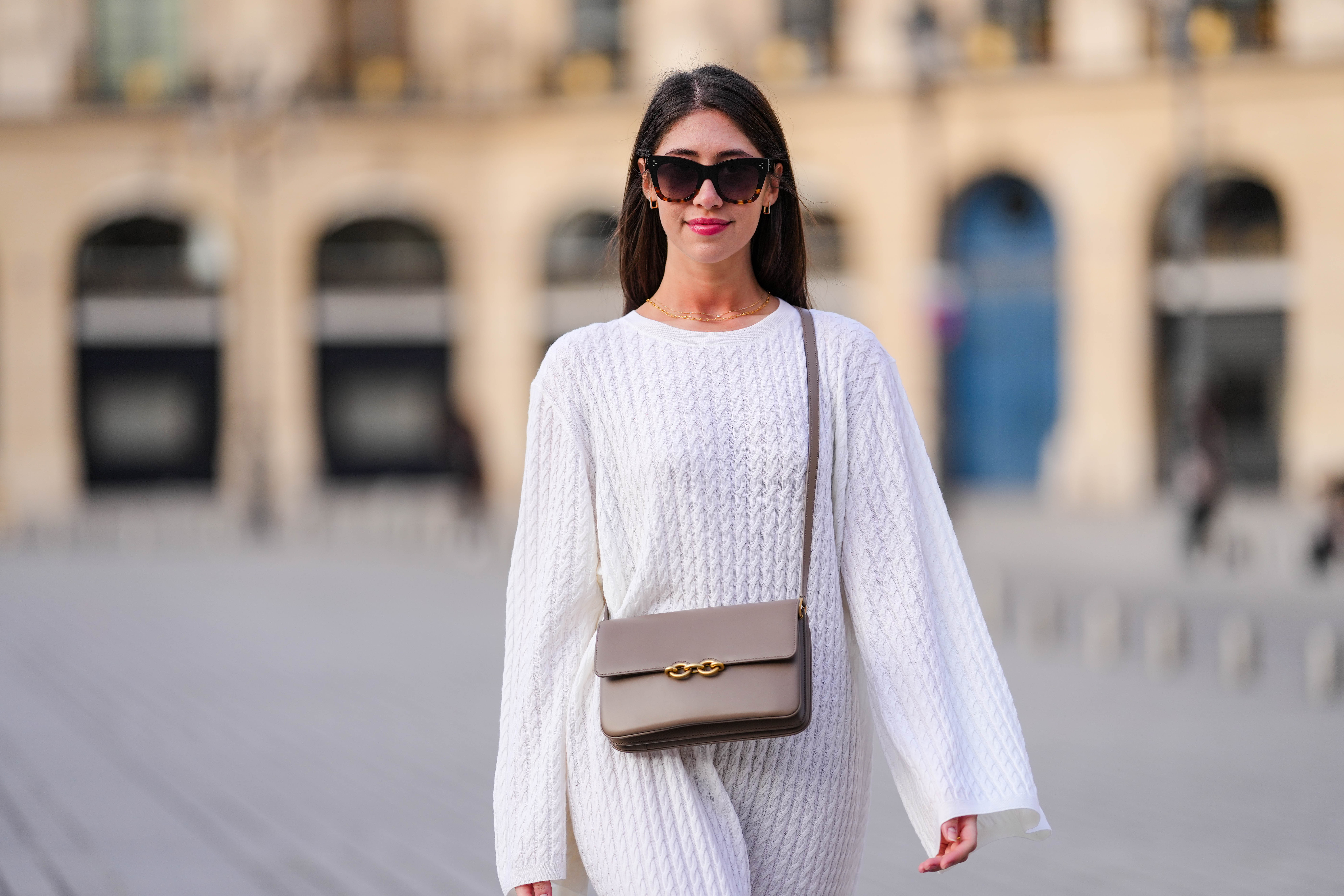 woman wearing loose white top and beige purse