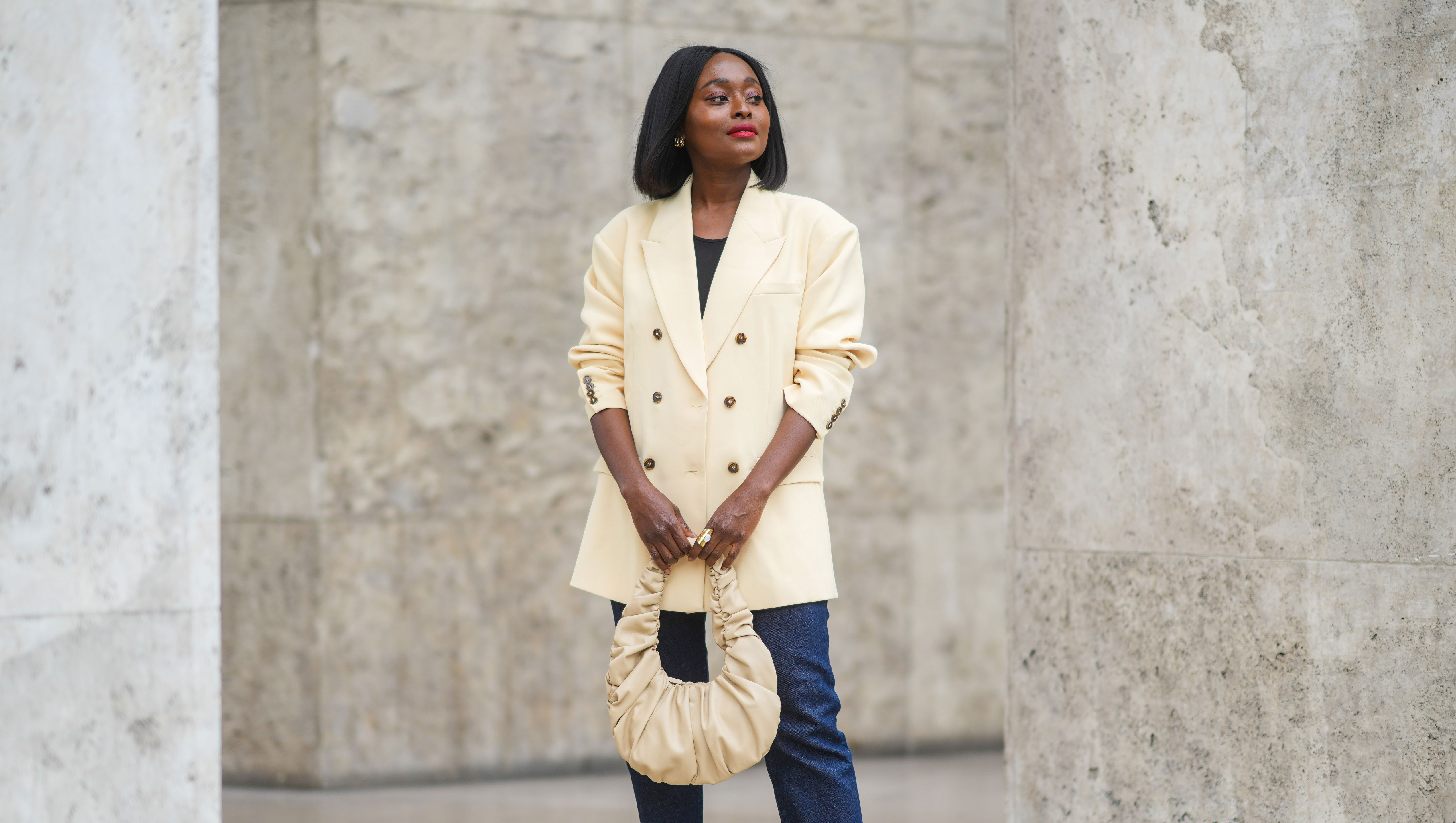 PARIS, FRANCE - JUNE 29: Carrole Sagba @linaose wears a beige oversized blazer jacket, a black top, blue denim jeans pants, a beige leather bag, a golden ring, yellow platform shoes, on June 29, 2021 in Paris, France. (Photo by Edward Berthelot/Getty Images)