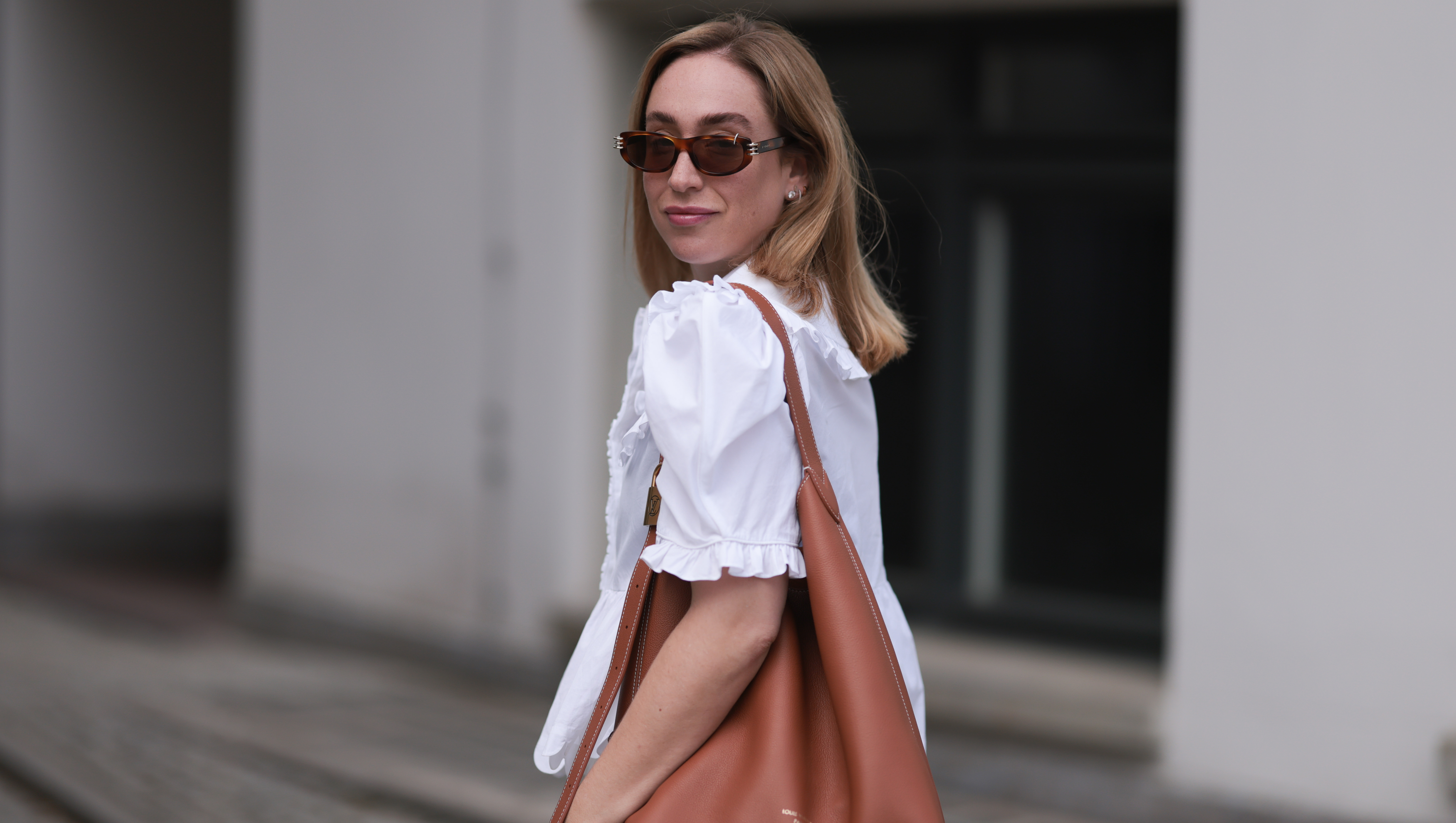 BERLIN, GERMANY - JUNE 11: Sonia Lyson is seen wearing sunglasses with havana frame from Givenchy, silver earrings, a golden necklace, a white blouse with puffed sleeves and ruffled details from Horror Vacui, cream-white wide linen pants from Zara and the &ldquo;Low Key Hobo&rdquo; bag in brown leather from Louis Vuitton on June 11, 2024 in Berlin, Germany. (Photo by Jeremy Moeller/Getty Images)