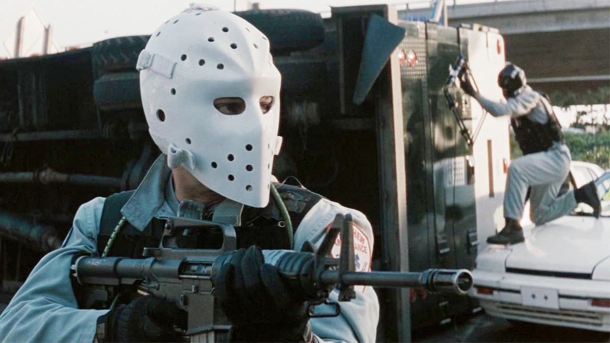 A man wearing a mask aims his gun in Heat.