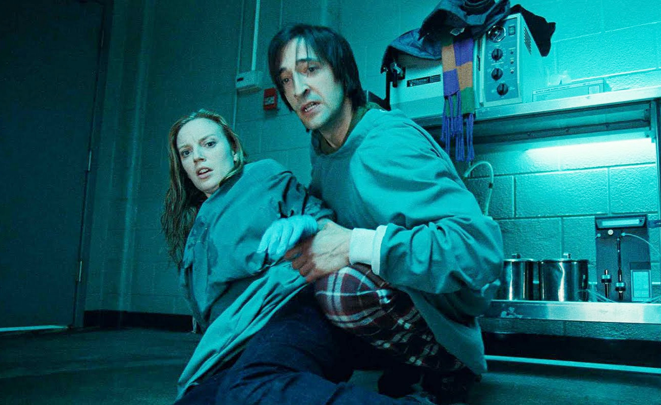 A man and a woman lean back in terror in Splice.