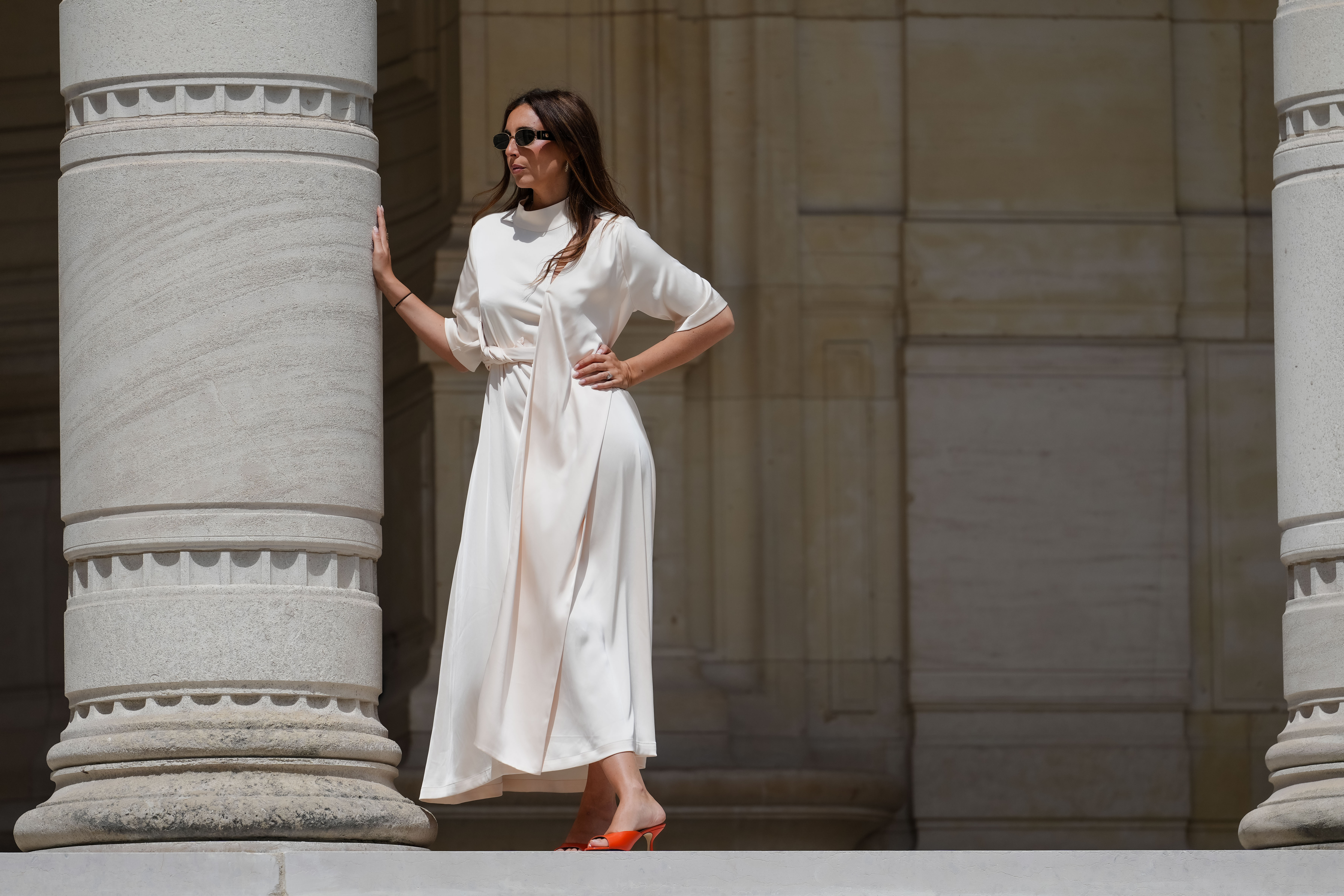 Gabriella Berdugo wears sunglasses, a white long gathered dress with a scarf from Gestuz, red kitten heels mule shoes with open toe from Age of Innocence, during a street style fashion photo session, on May 16, 2024 in Paris, France.