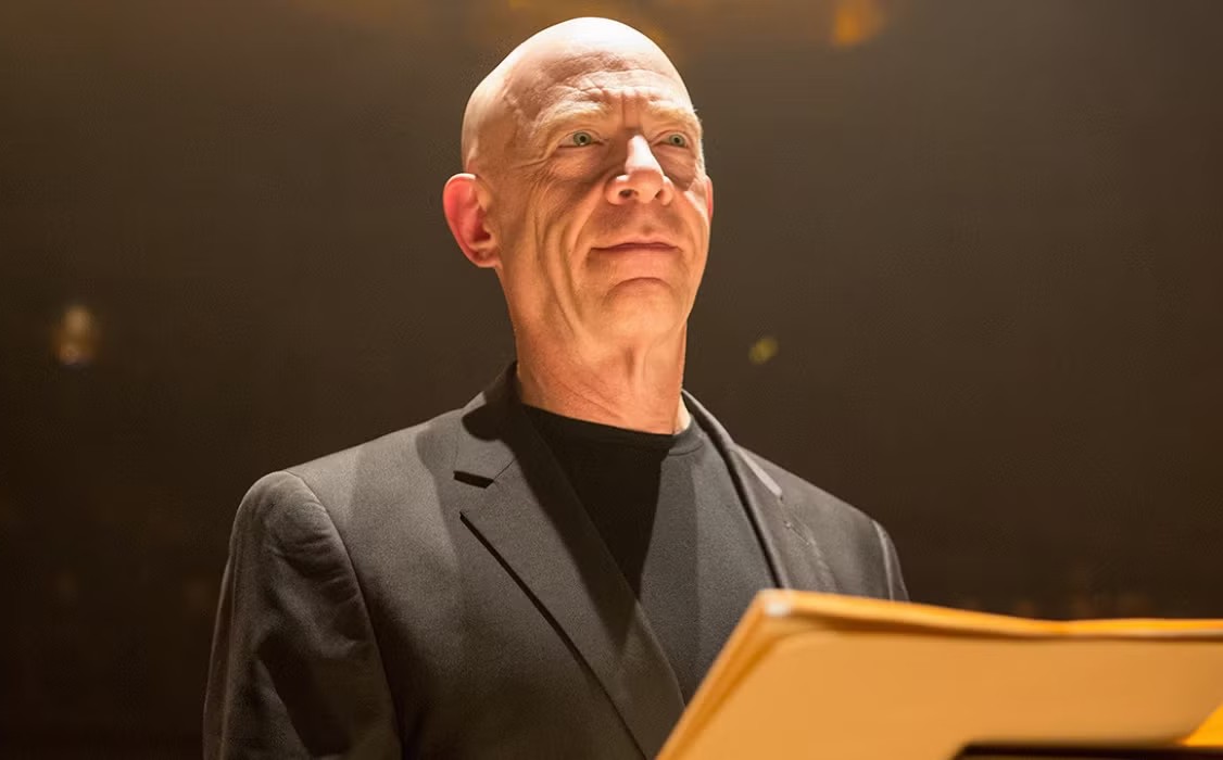 A man stands in front of a lectern in Whiplash.