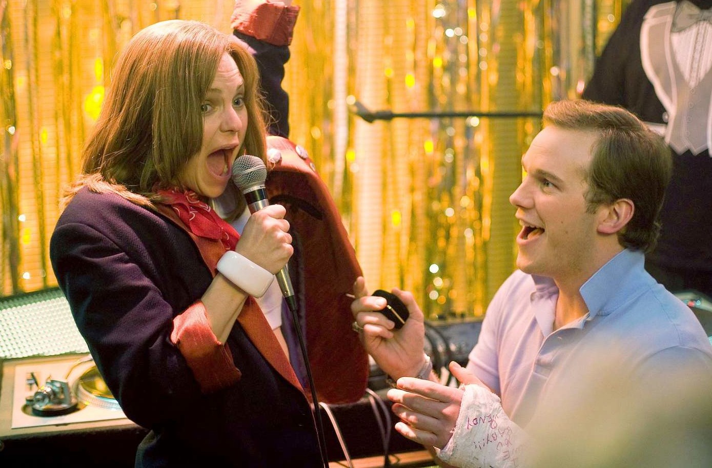 A guy looks at a girl singing in Take Me Home Tonight.