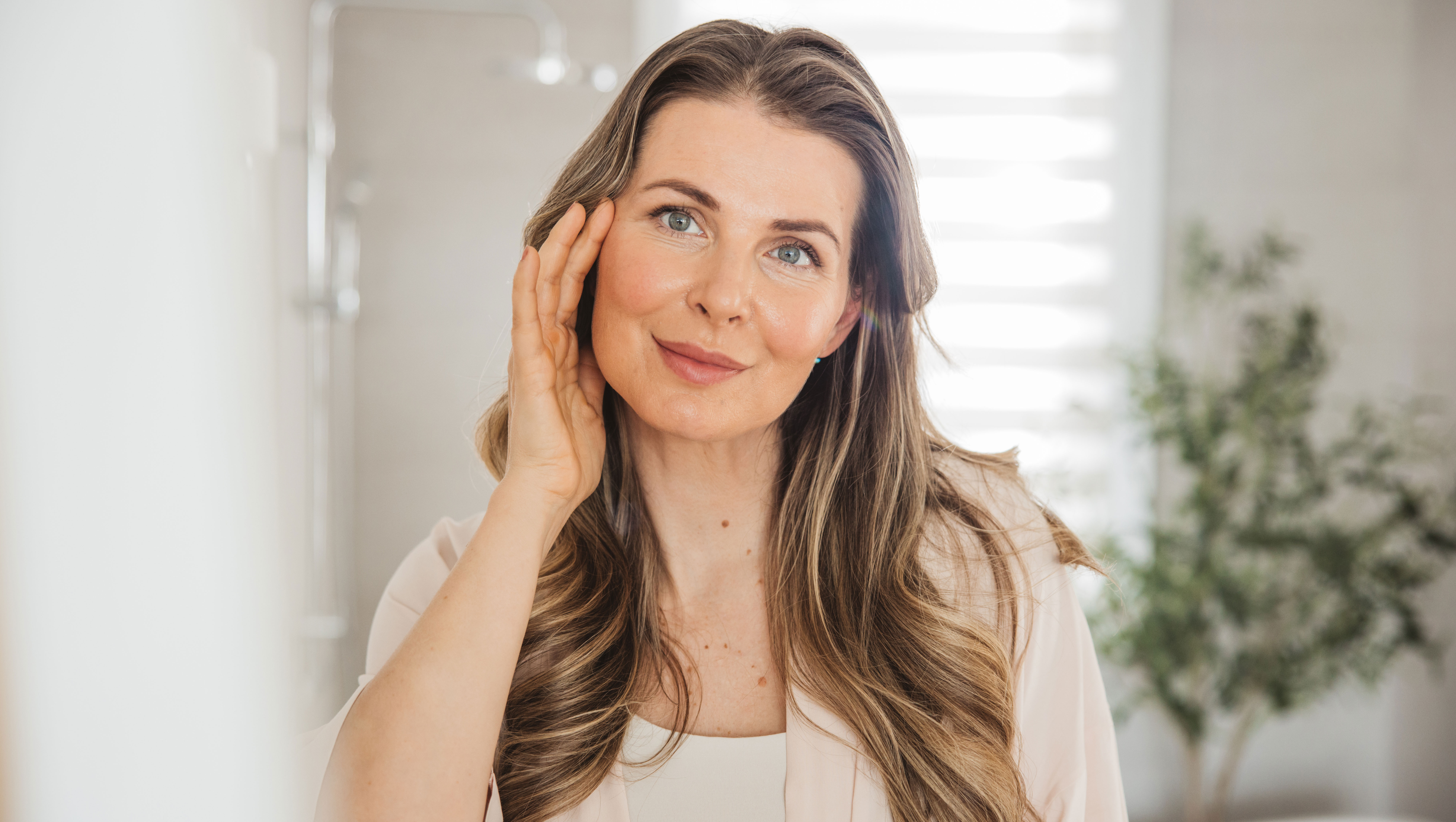 Mature woman applying moisturizer on face - stock photo